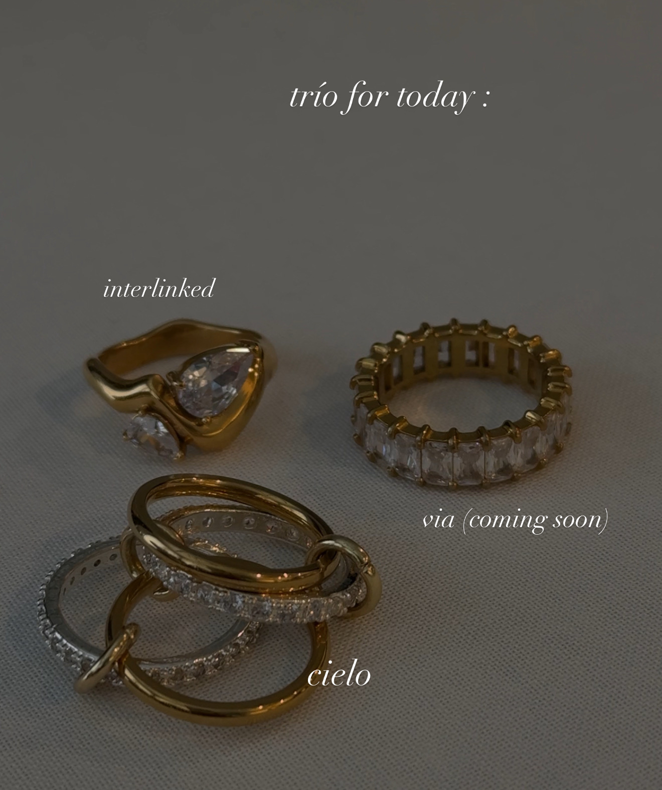 Four rings displayed on a surface with text labels, including one with a large gemstone and others with intricate designs.