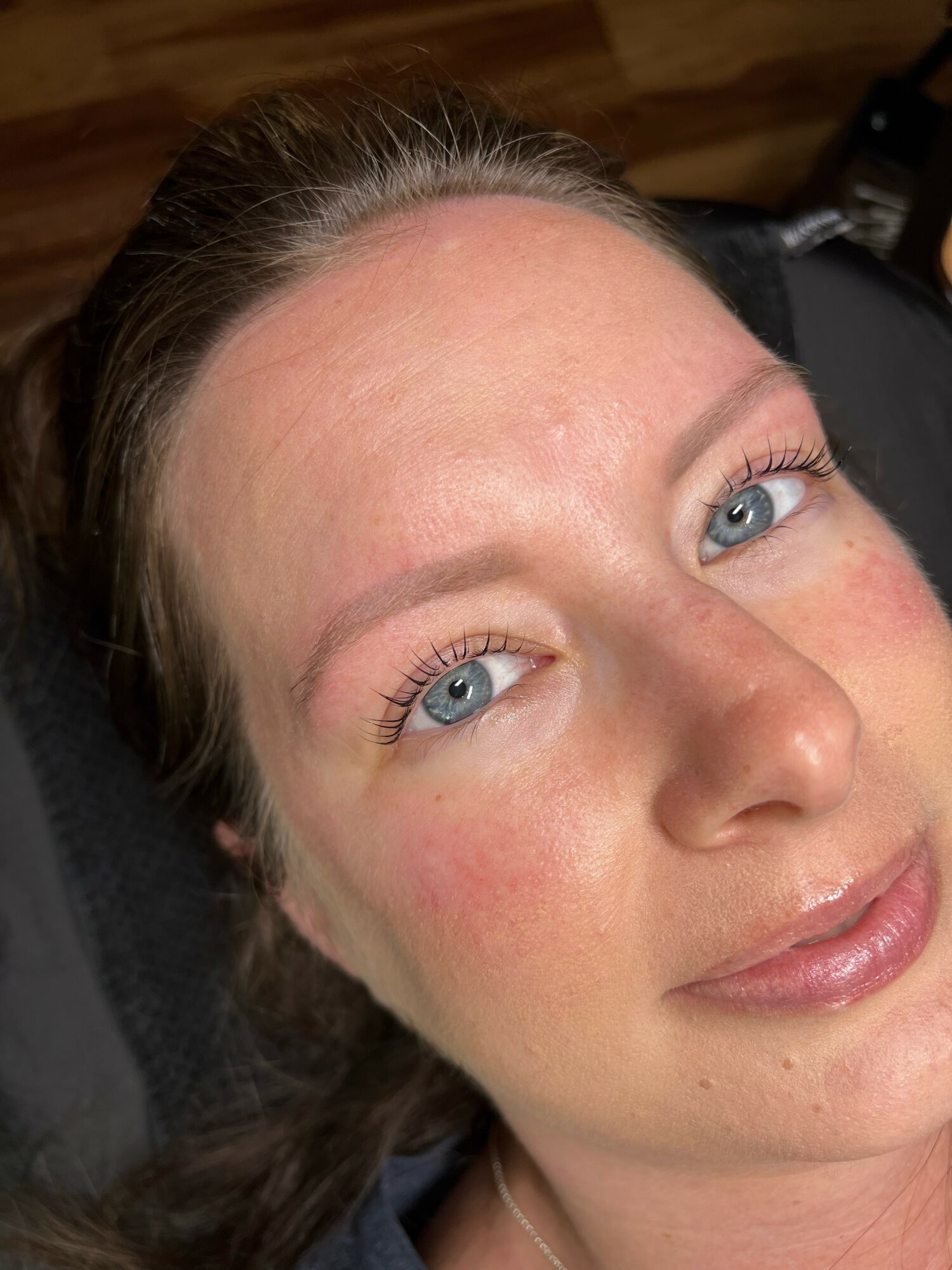 Close-up of a woman with blue eyes, light skin, and brown hair, lying down with a neutral expression.