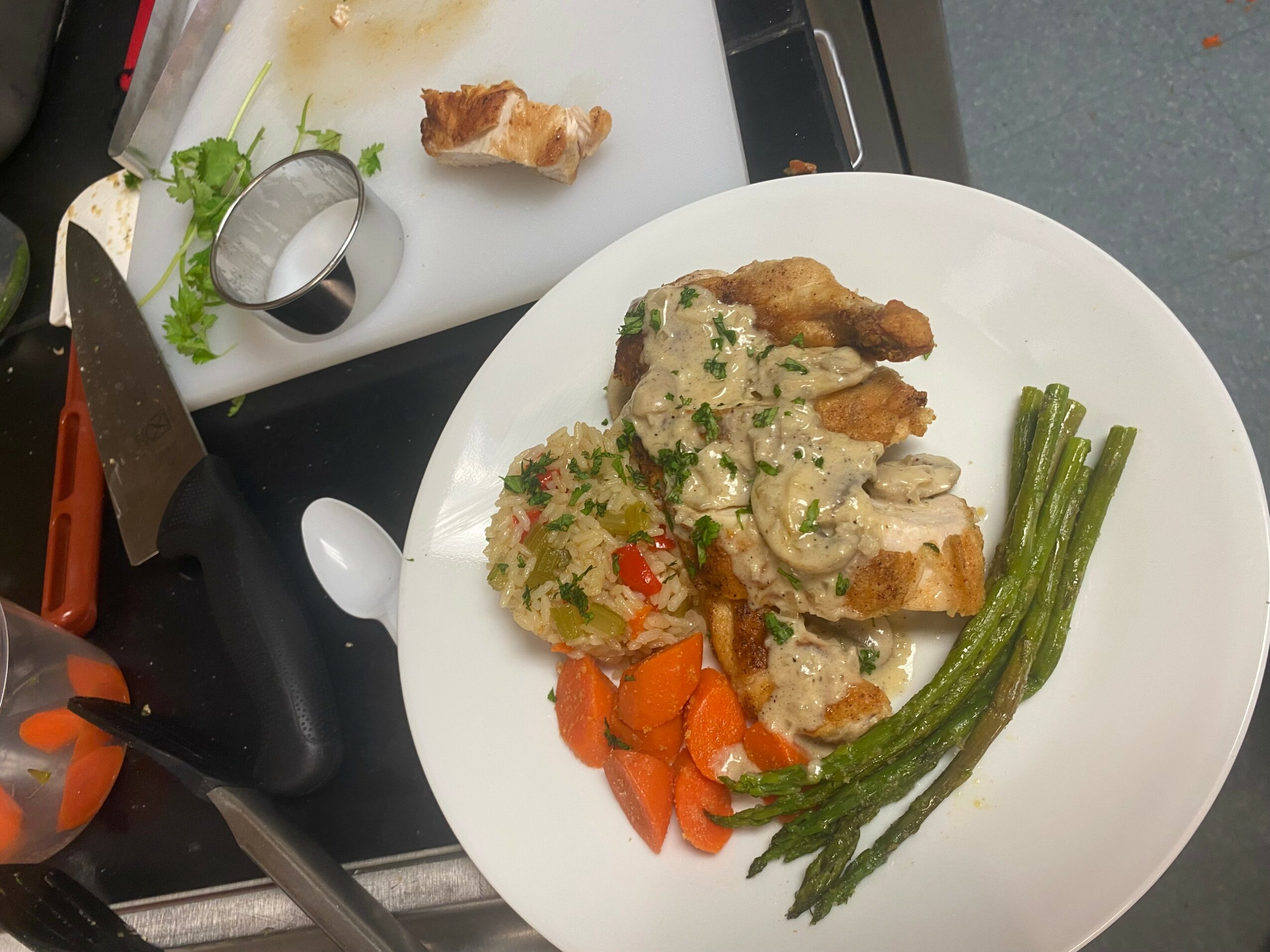 Plate with chicken, creamy mushroom sauce, carrots, and green beans on a white dish.