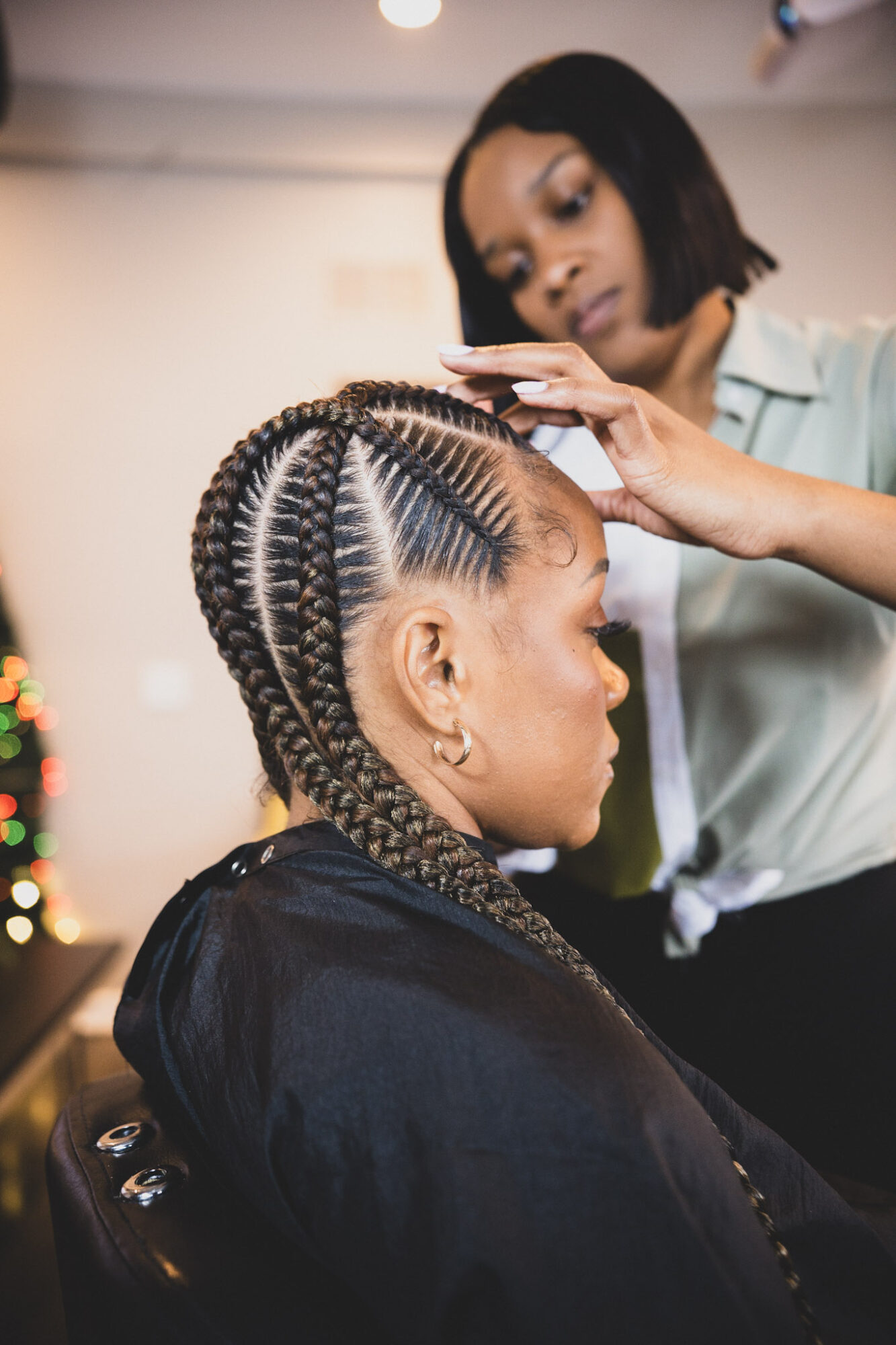 Woman with braided hairstyle getting hair styled by a professional in a salon.