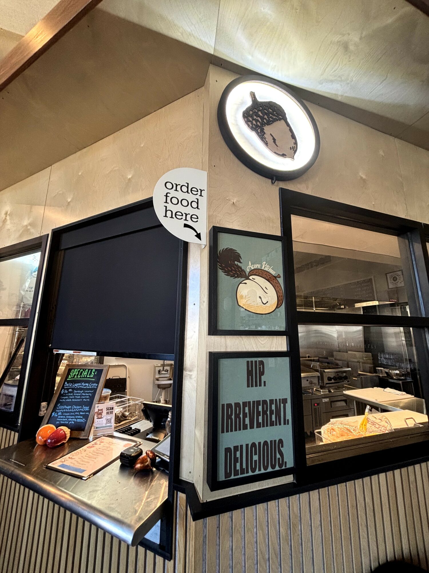 Corner of a food establishment with signs, framed pictures, and a display case, featuring a sign that says 'order food here'.