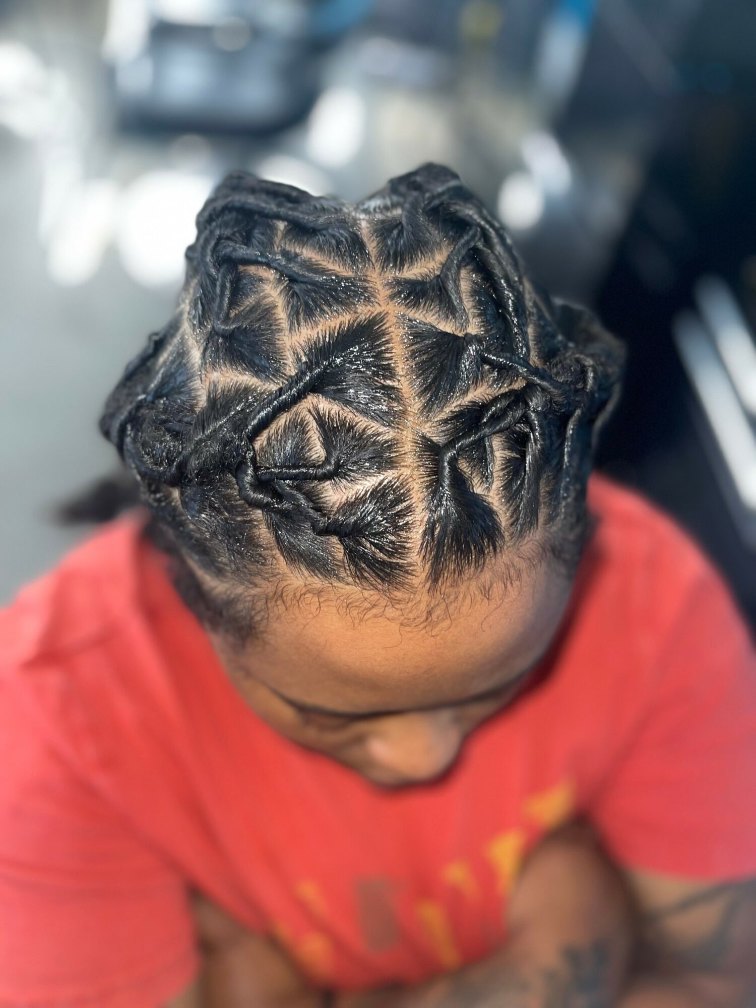 Top view of a person with braided hairstyle featuring multiple sections and intricate patterning.