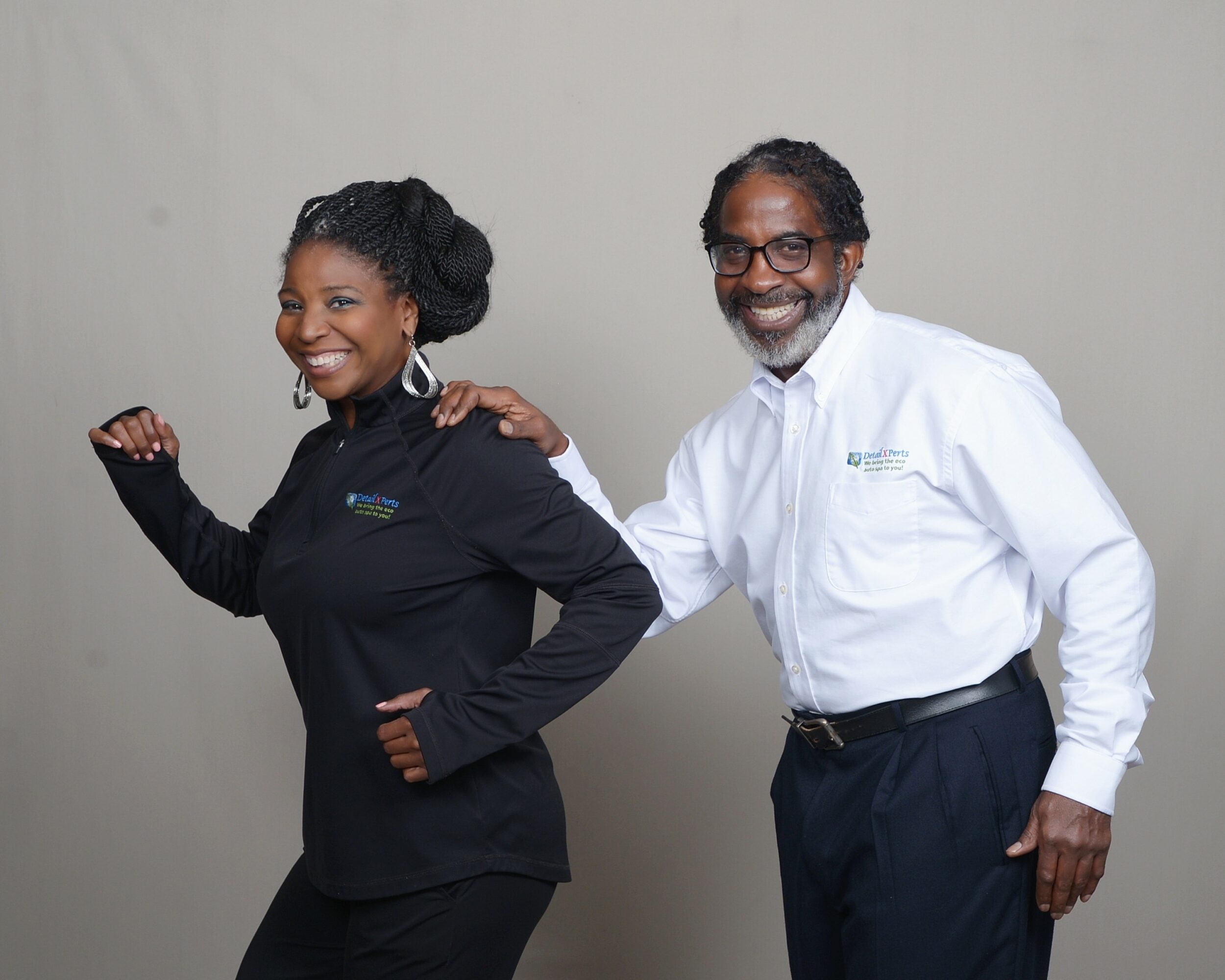 Two smiling professionals, a woman and a man, stand side by side against a plain background.