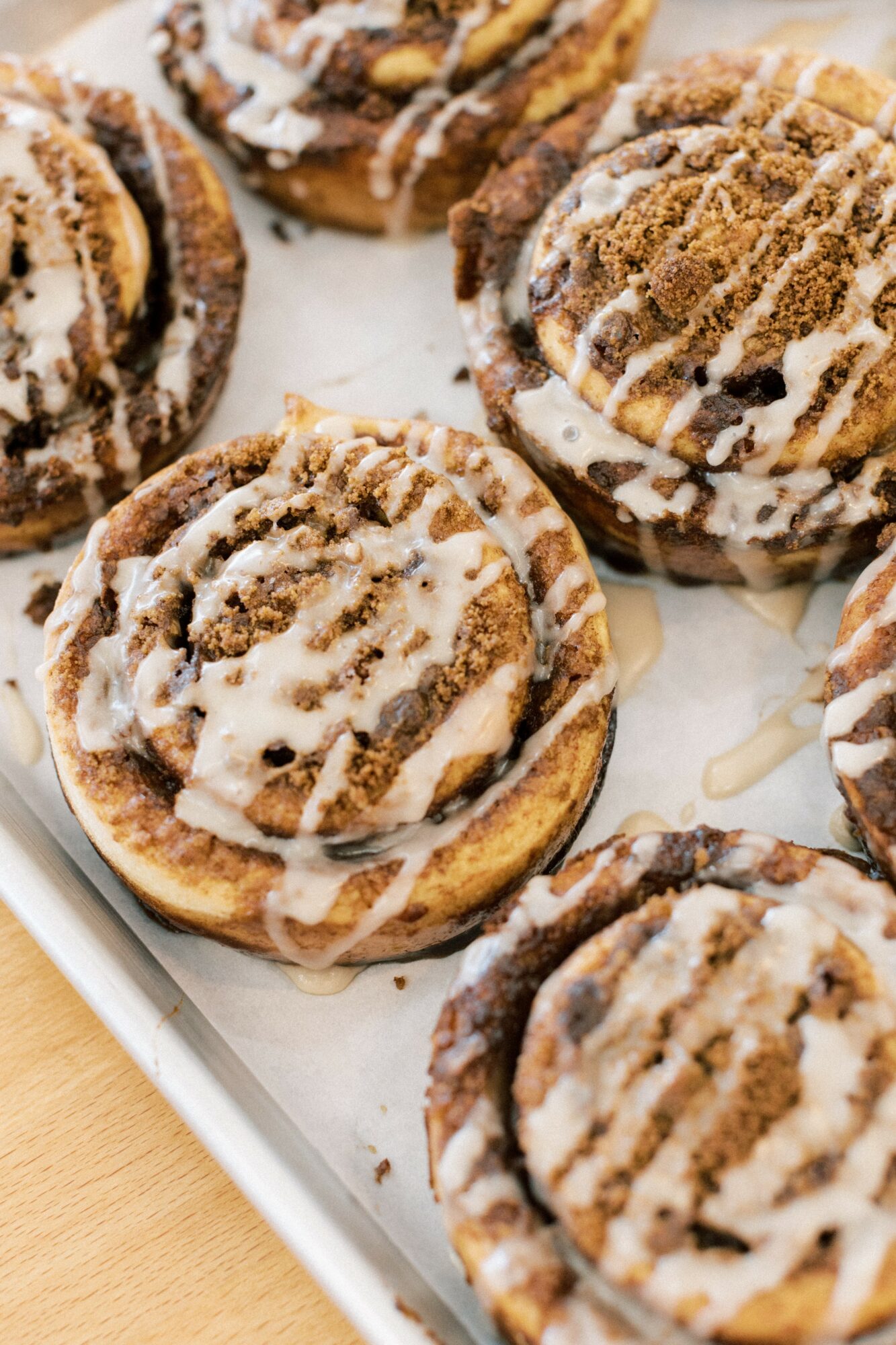 Close-up of cinnamon rolls with icing on a tray, showing swirls and toppings.