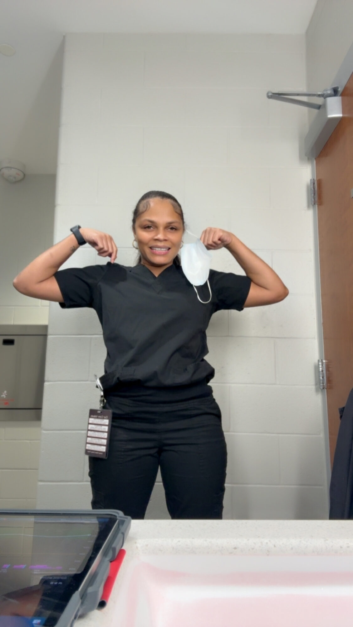 Person smiling and flexing arms in a room with white walls and a door.