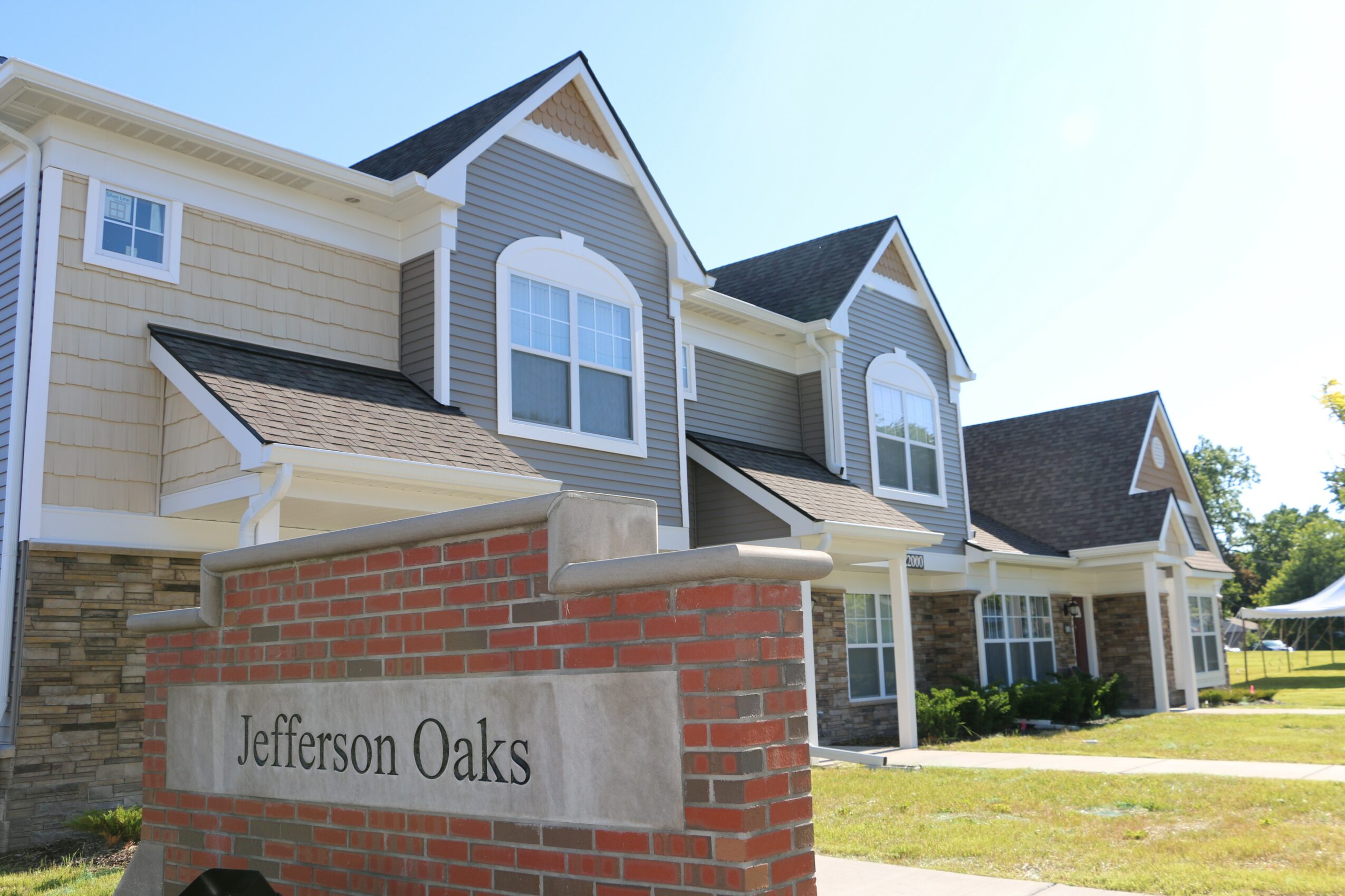 Residential building with brick and siding exterior, multiple gabled roofs, and a lawn in front.