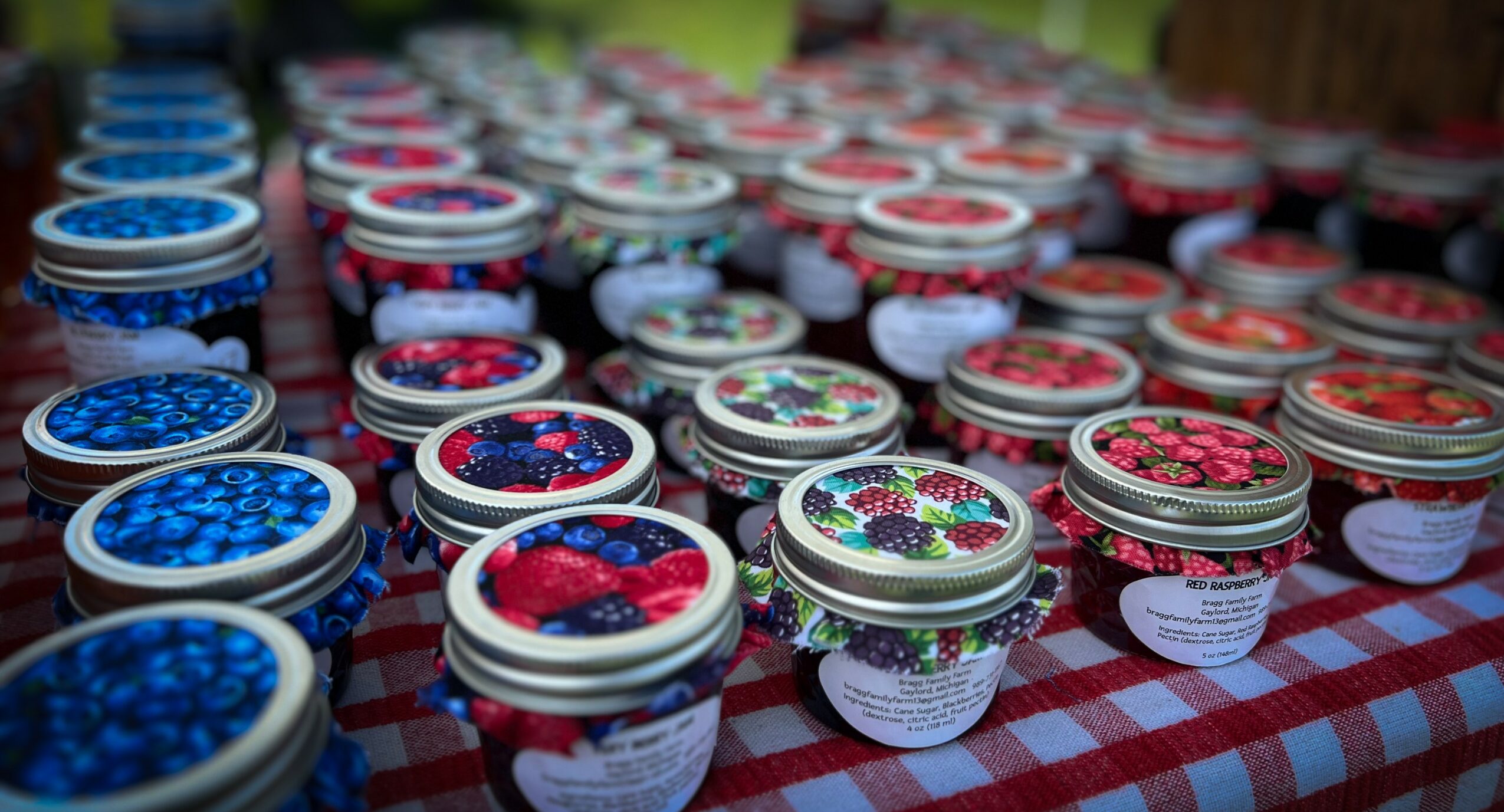 Multiple jars filled with colorful berries arranged on a checkered tablecloth.