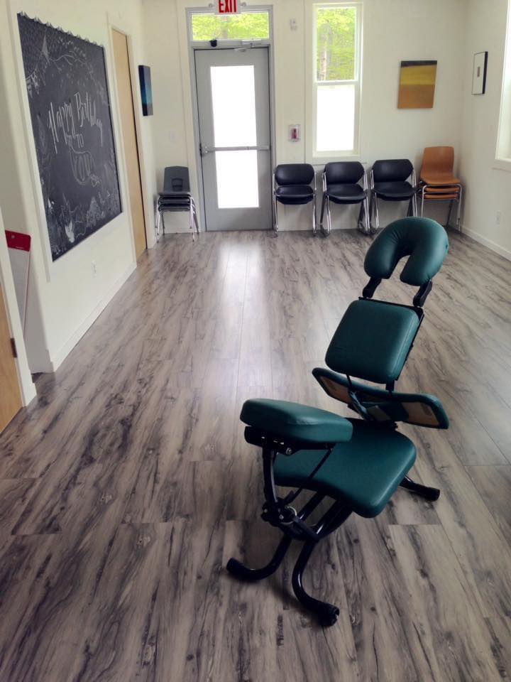 Empty room with chairs, a chalkboard, and a door with windows, wood floor, and white walls.
