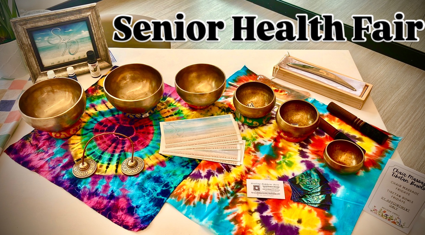Display of singing bowls, face masks, and informational materials on colorful tie-dye cloth at Senior Health Fair.