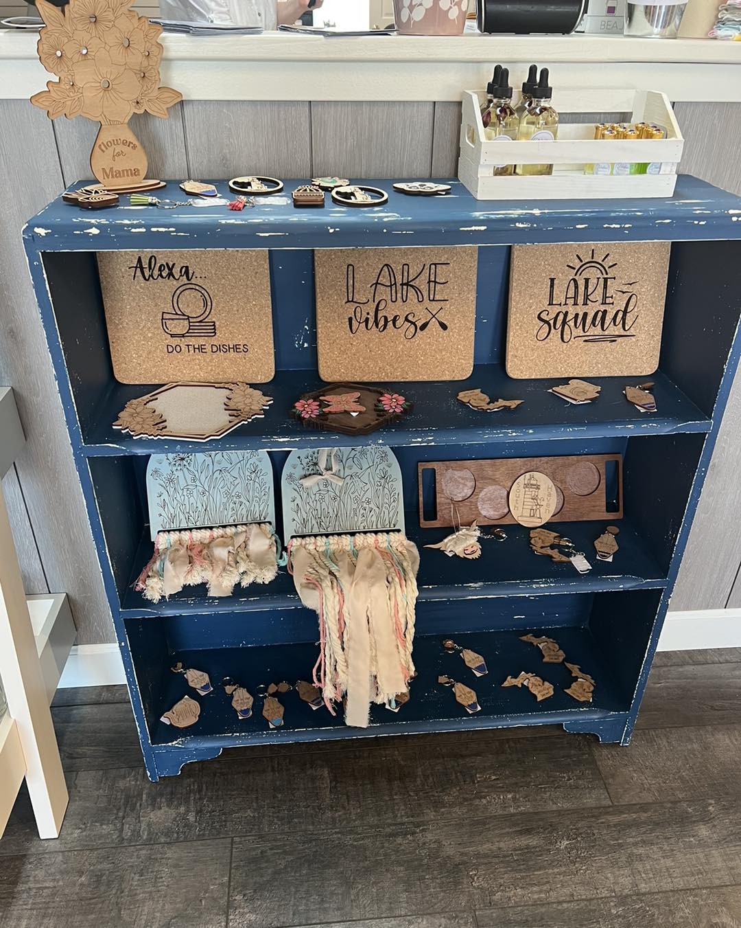 Blue shelf with signs, boxes, and decorations, including a cloth with fringe hanging from the middle shelf.