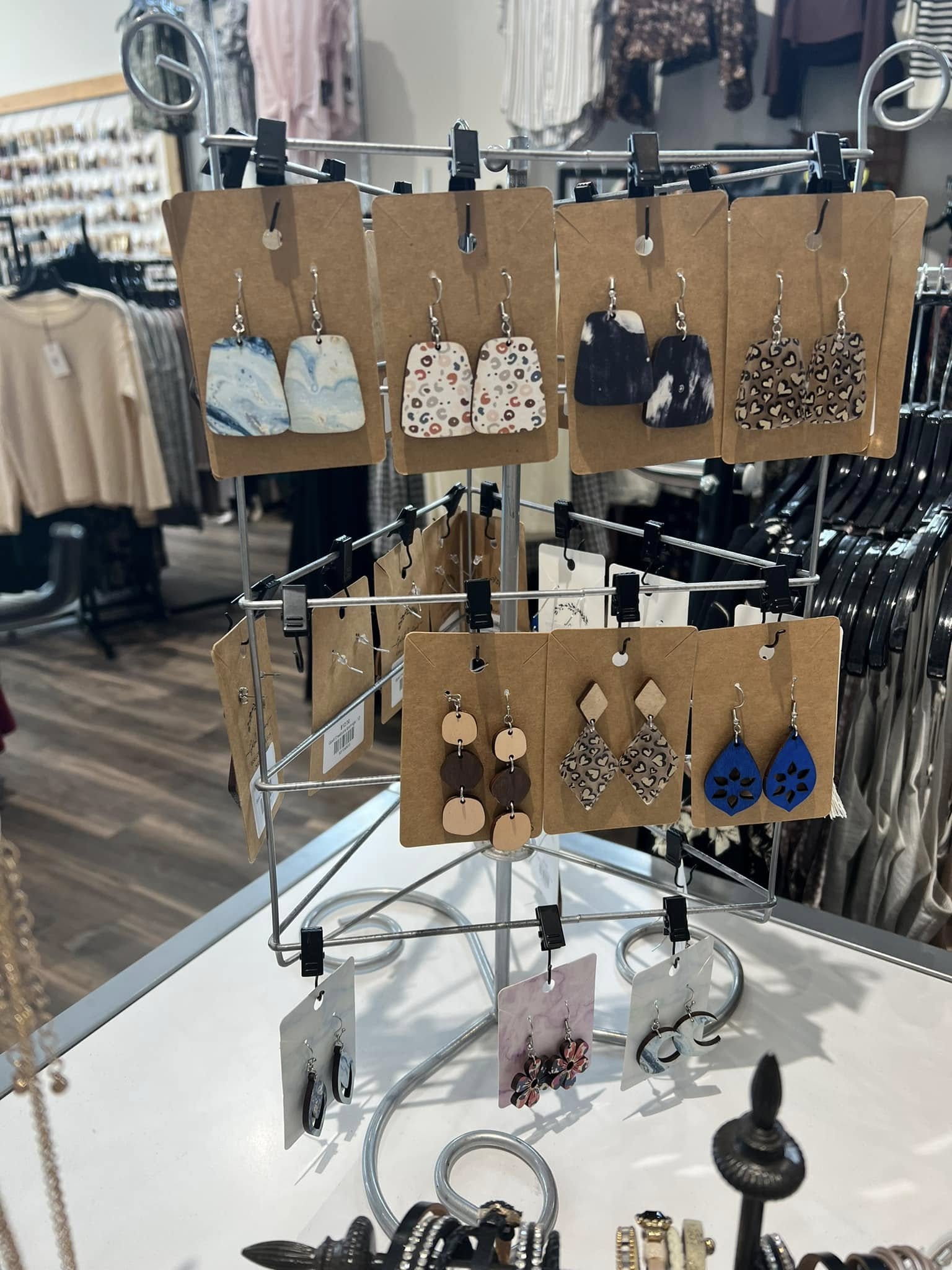 Display stand with earrings on brown cards, arranged in two rows, in a clothing store setting.