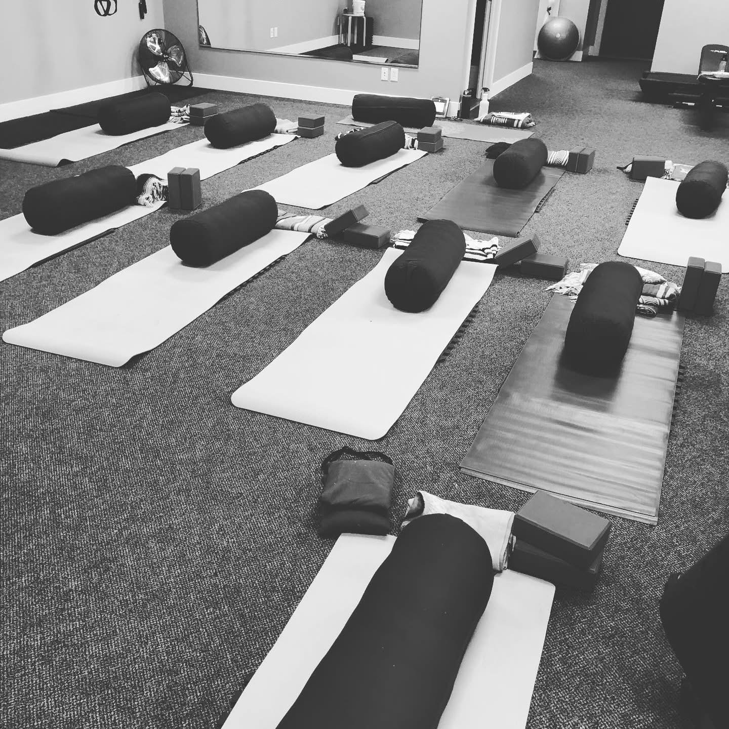Yoga mats with bolsters and weights arranged in a fitness studio, ready for class.