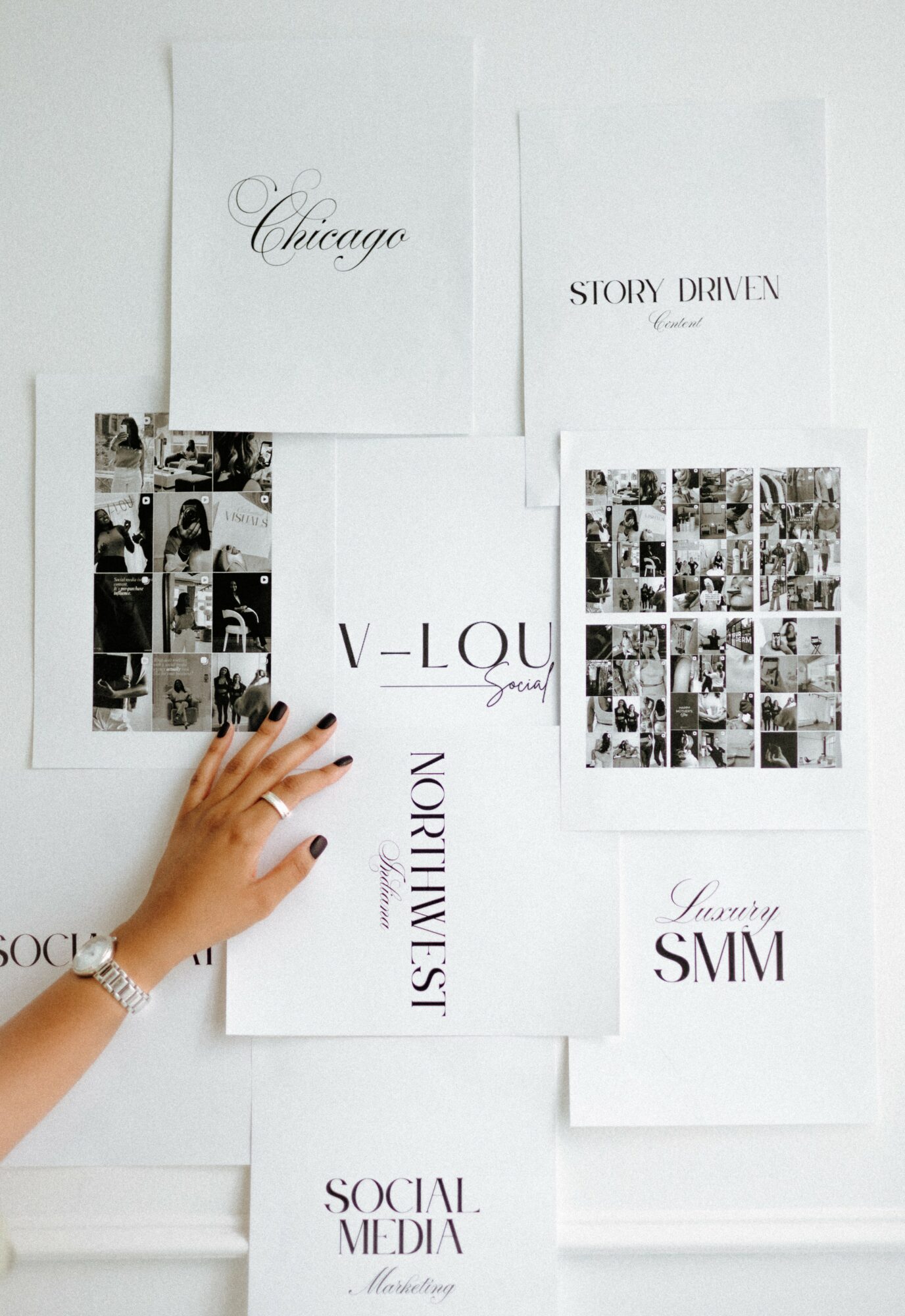 Hand with a watch and bracelet points to a collage of black-and-white photos on a white background, surrounded by various paper sheets.