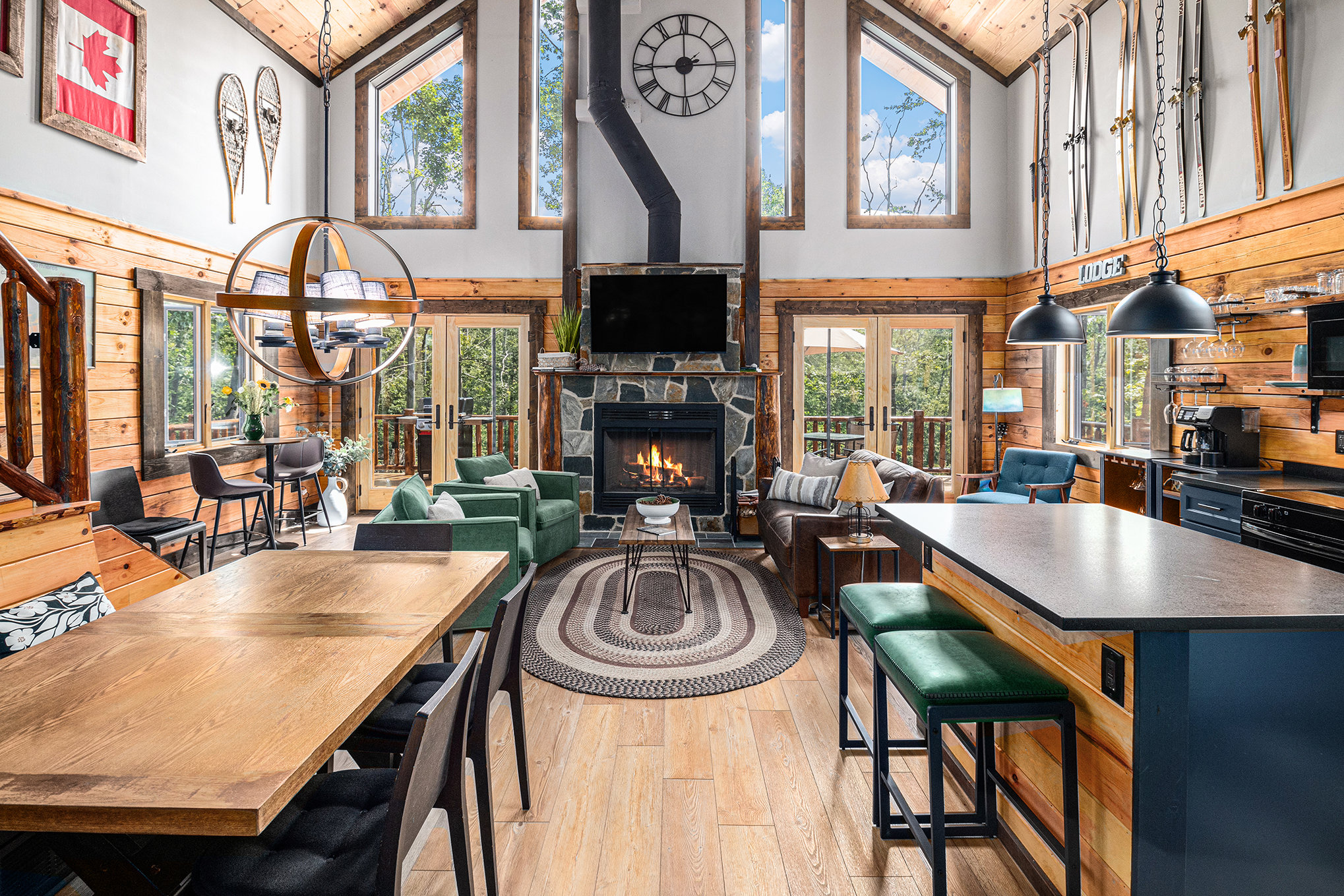 Spacious living room with large windows, a fireplace, and modern furniture, including a dining table, sofas, and bar stools.