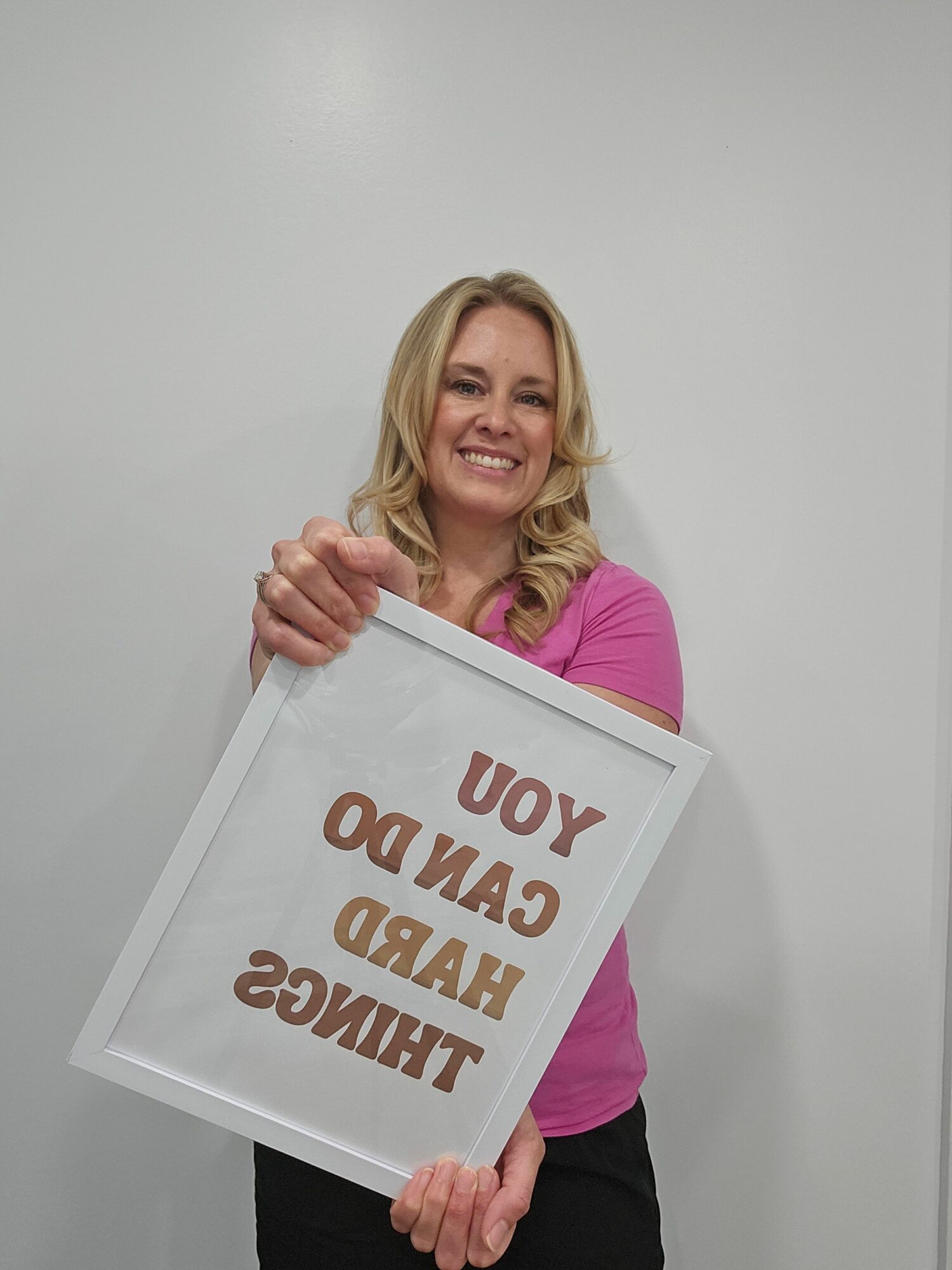 Woman holding a sign with the message 'YOU AND ME HAD A GOOD TIME' in large letters, smiling, against a plain background.