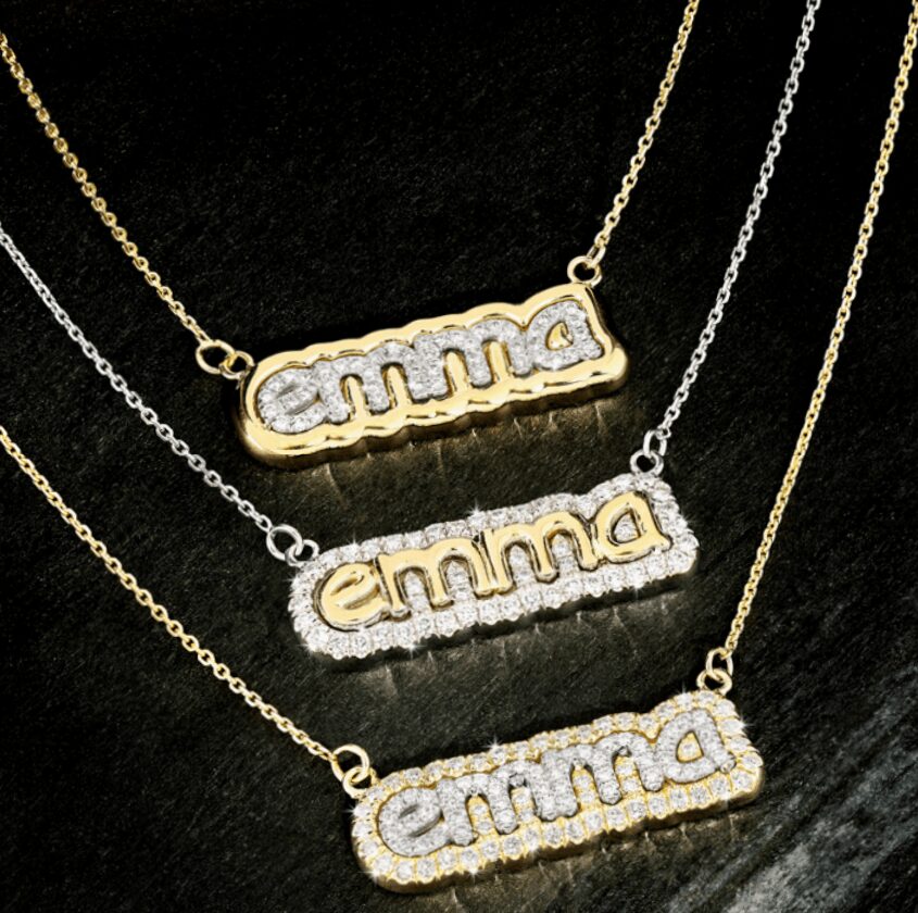 Three necklaces with name pendants spelling 'emma' in gold and silver, decorated with small stones, on a dark background.