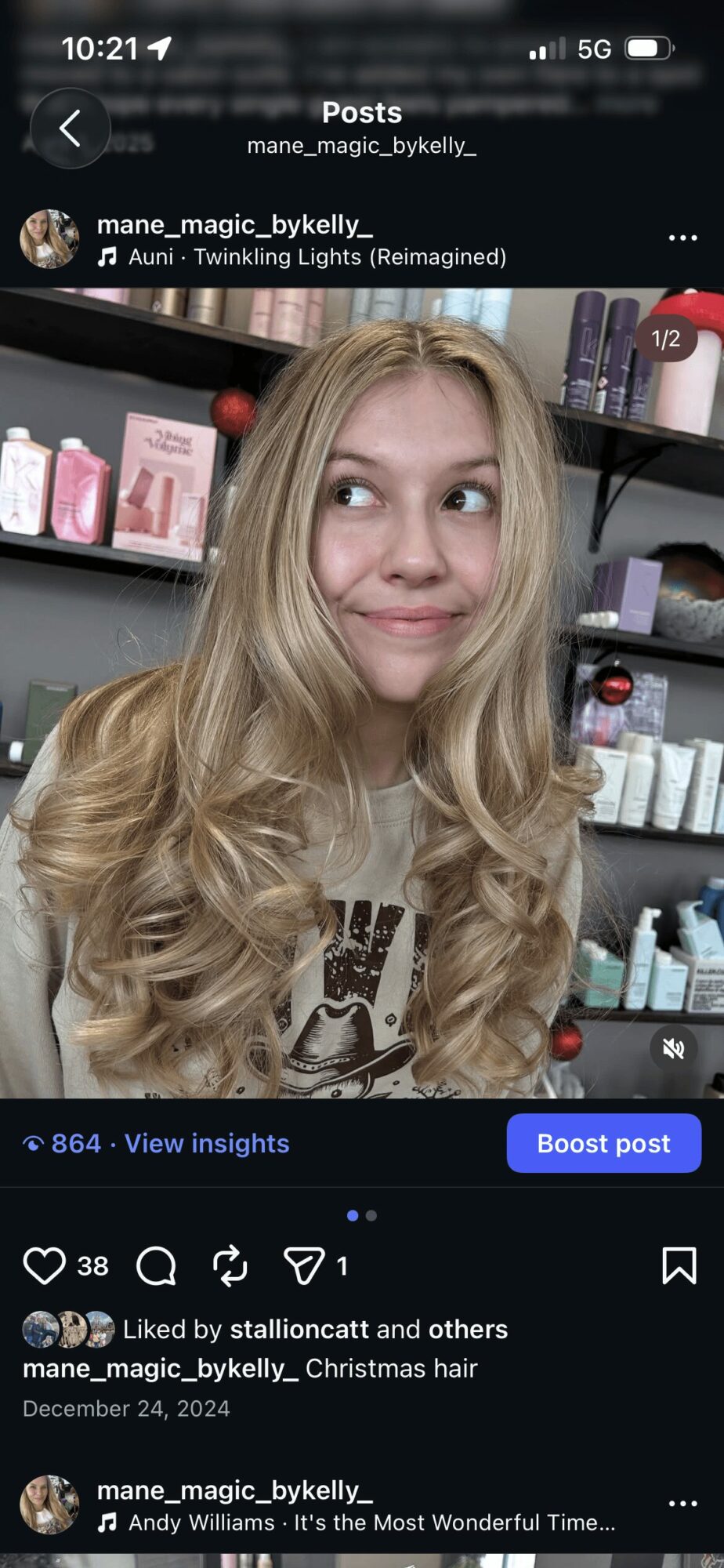 Young woman with long, wavy blonde hair smiling in a store with shelves of products behind her.