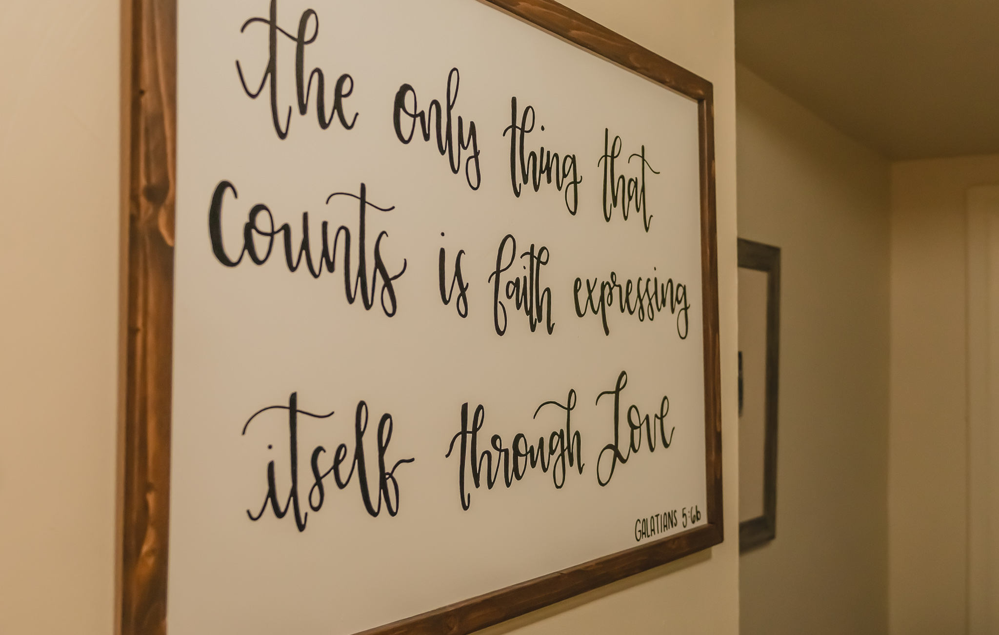 Framed wall art with a quote in cursive and print reading, 'the only thing that counts is faith expressing itself through love.'