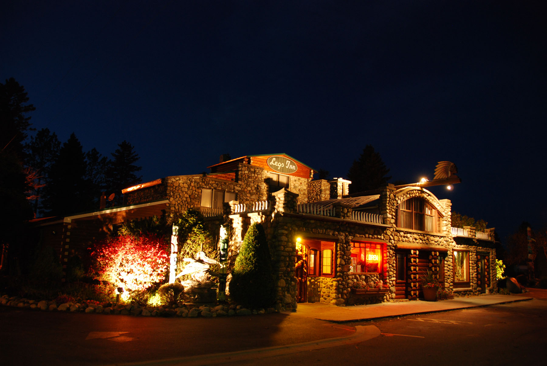 Night view of a lit building with trees in the background, illuminated by exterior lights, with a dark sky above.
