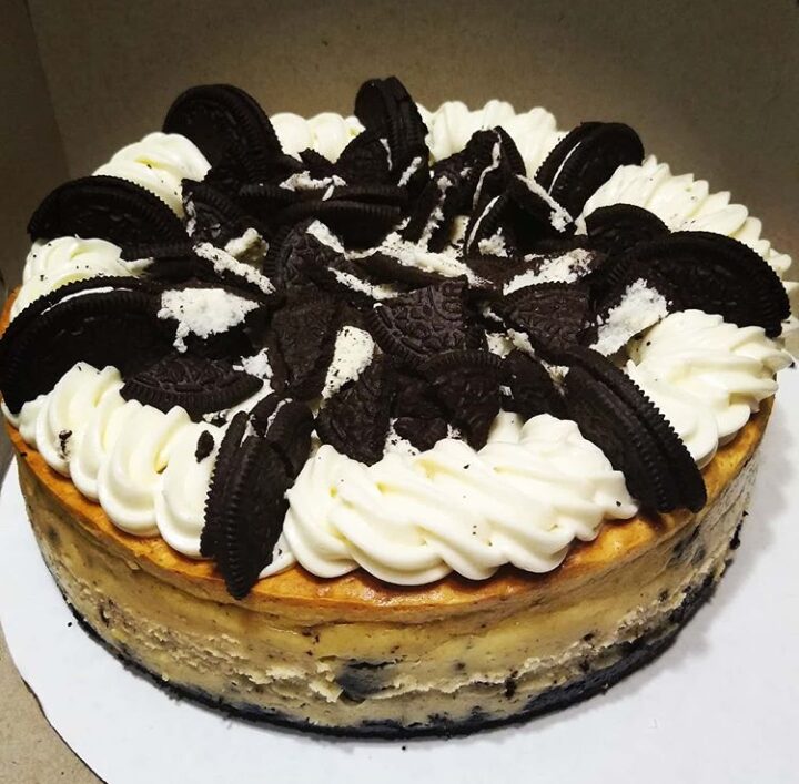 Oreo cheesecake with whipped cream and Oreo cookies on top, in a round pan, viewed from above.