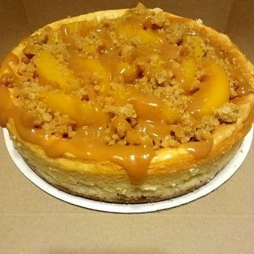 Peach cobbler with caramel sauce on top, in a round dish, on a white plate, viewed from above.