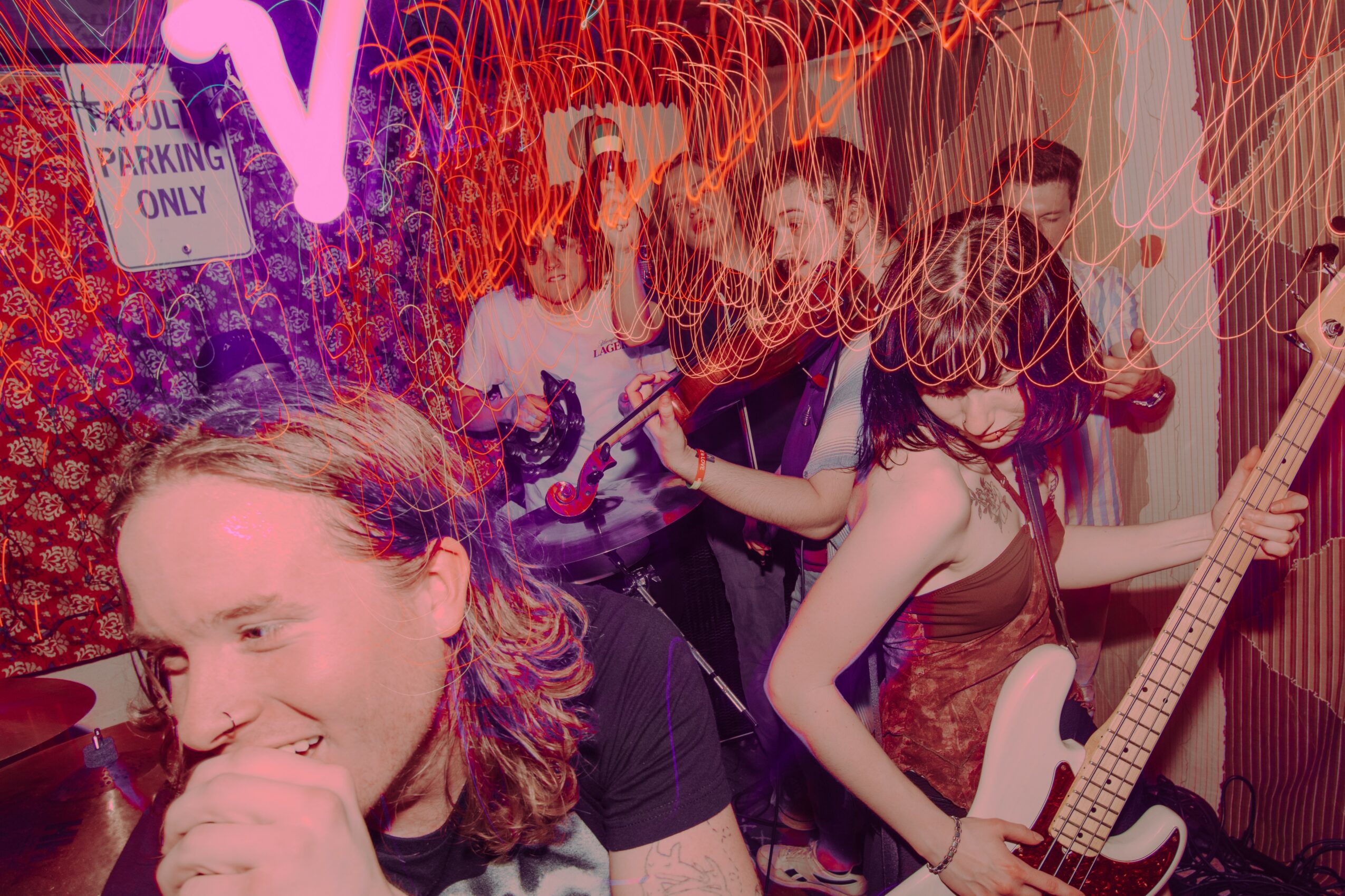 People dancing and playing guitars in a lively, colorful party scene with neon lights.