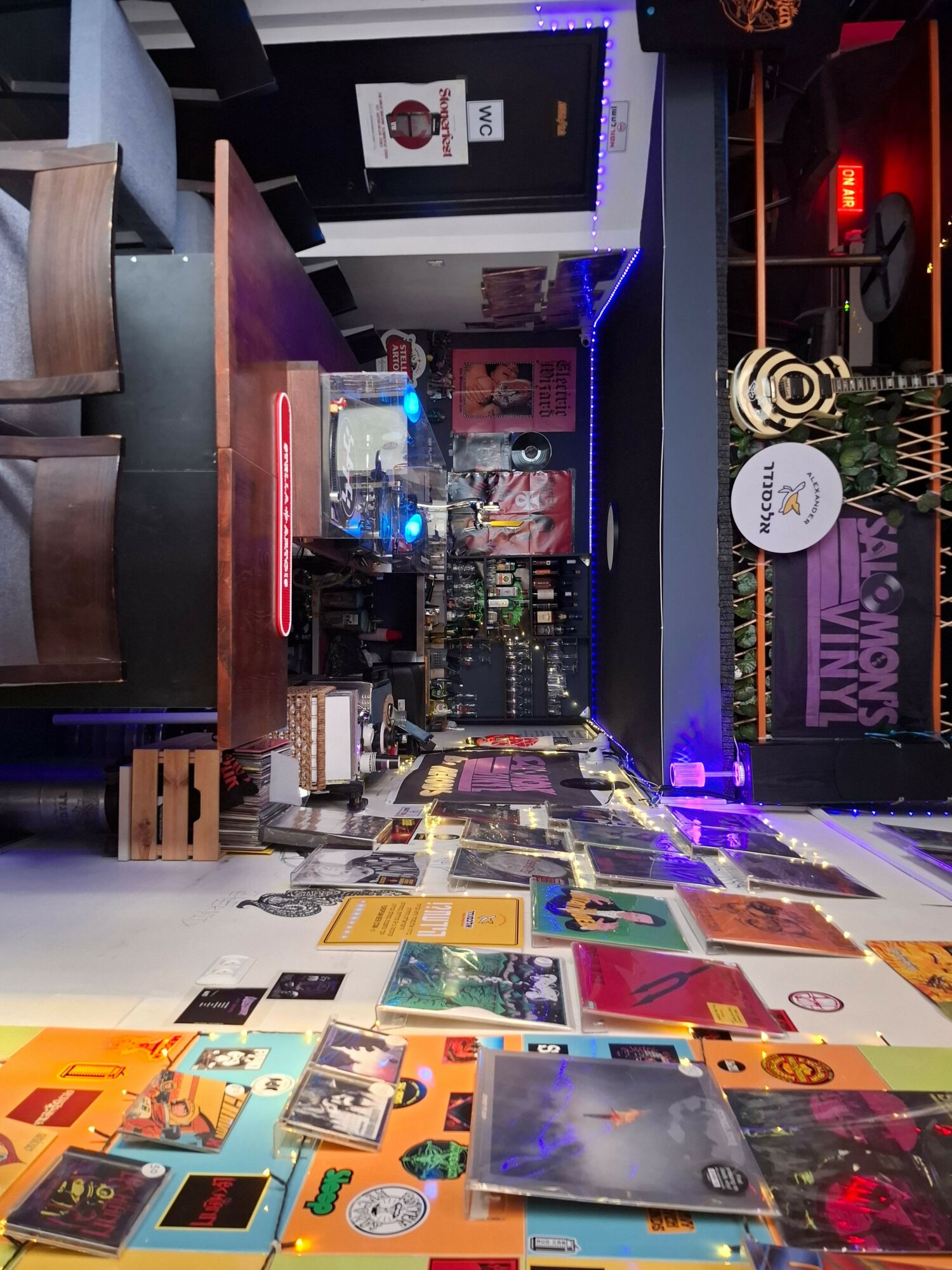 Indoor space with tables, chairs, and colorful wall decorations, including posters and photos, with a bar area in the background.