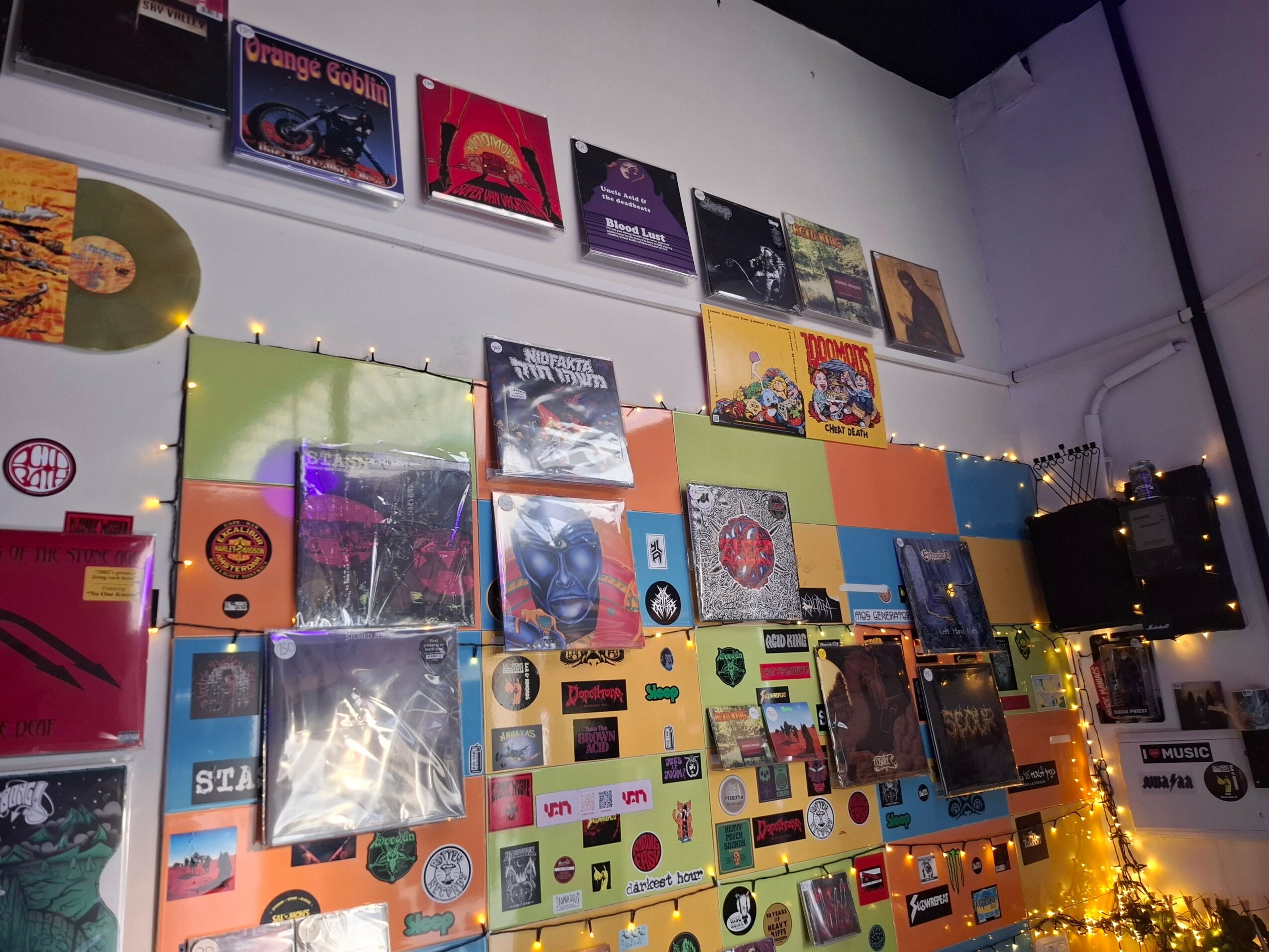 Wall decorated with colorful vinyl records, books, and string lights, creating a vibrant display.
