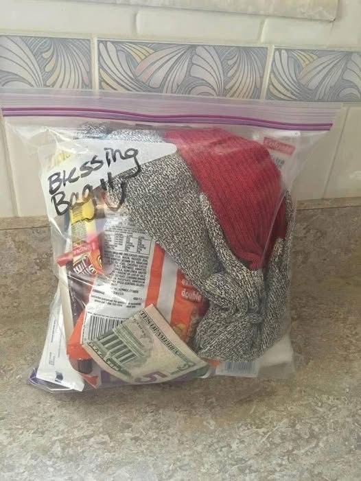 Clear plastic bag containing socks, a snack, and cash, placed on a countertop with decorative tiles in the background.