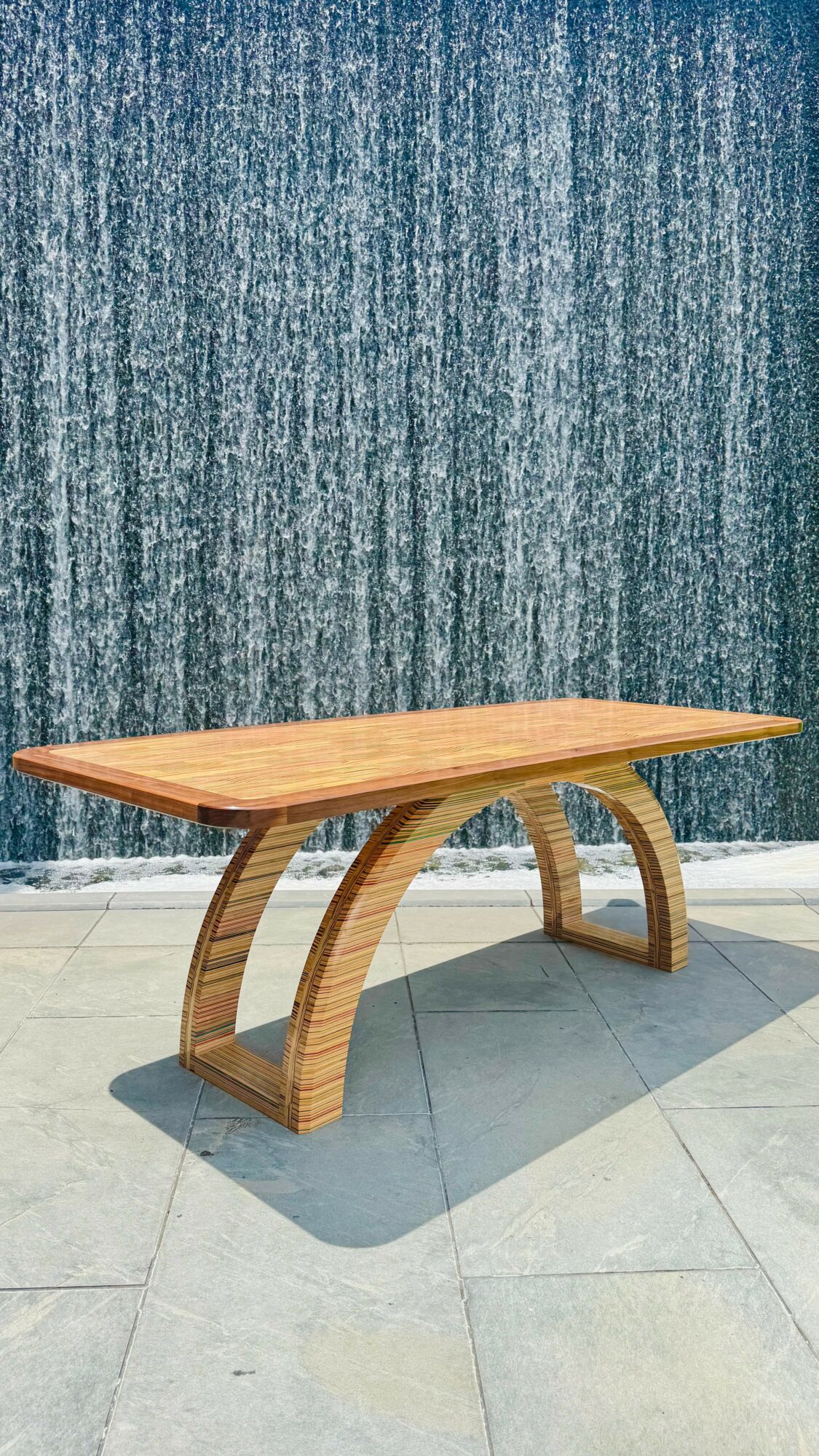 Wooden table with curved legs on tiled floor against a textured blue wall.
