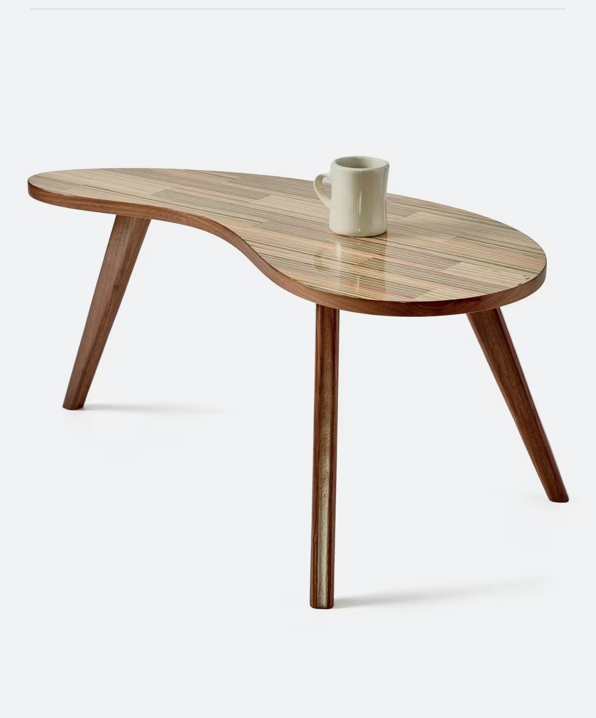 Wooden table with three legs and a mug on top, against a plain background.