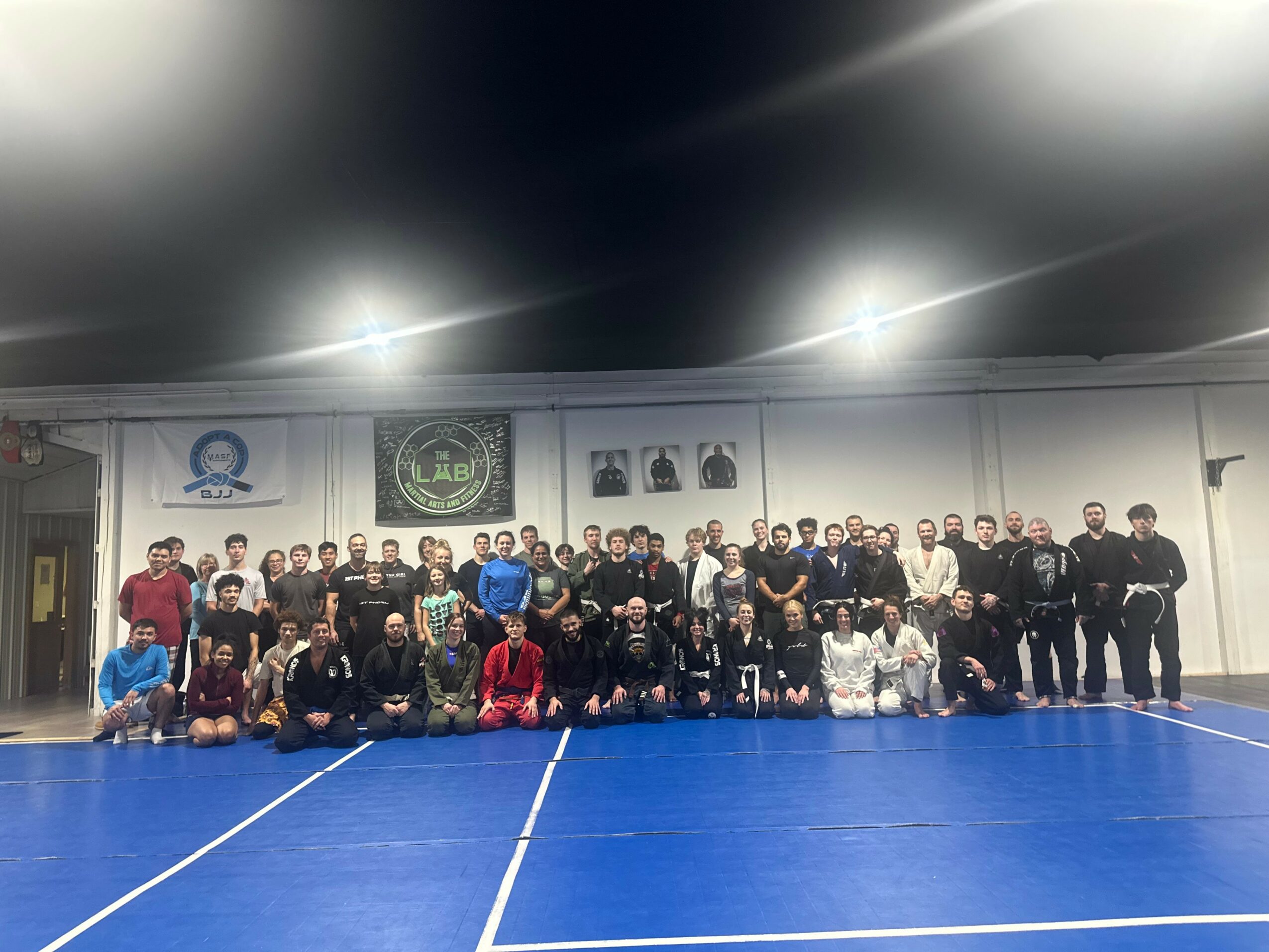Group of people posing on an indoor sports court with banners on the wall behind them.
