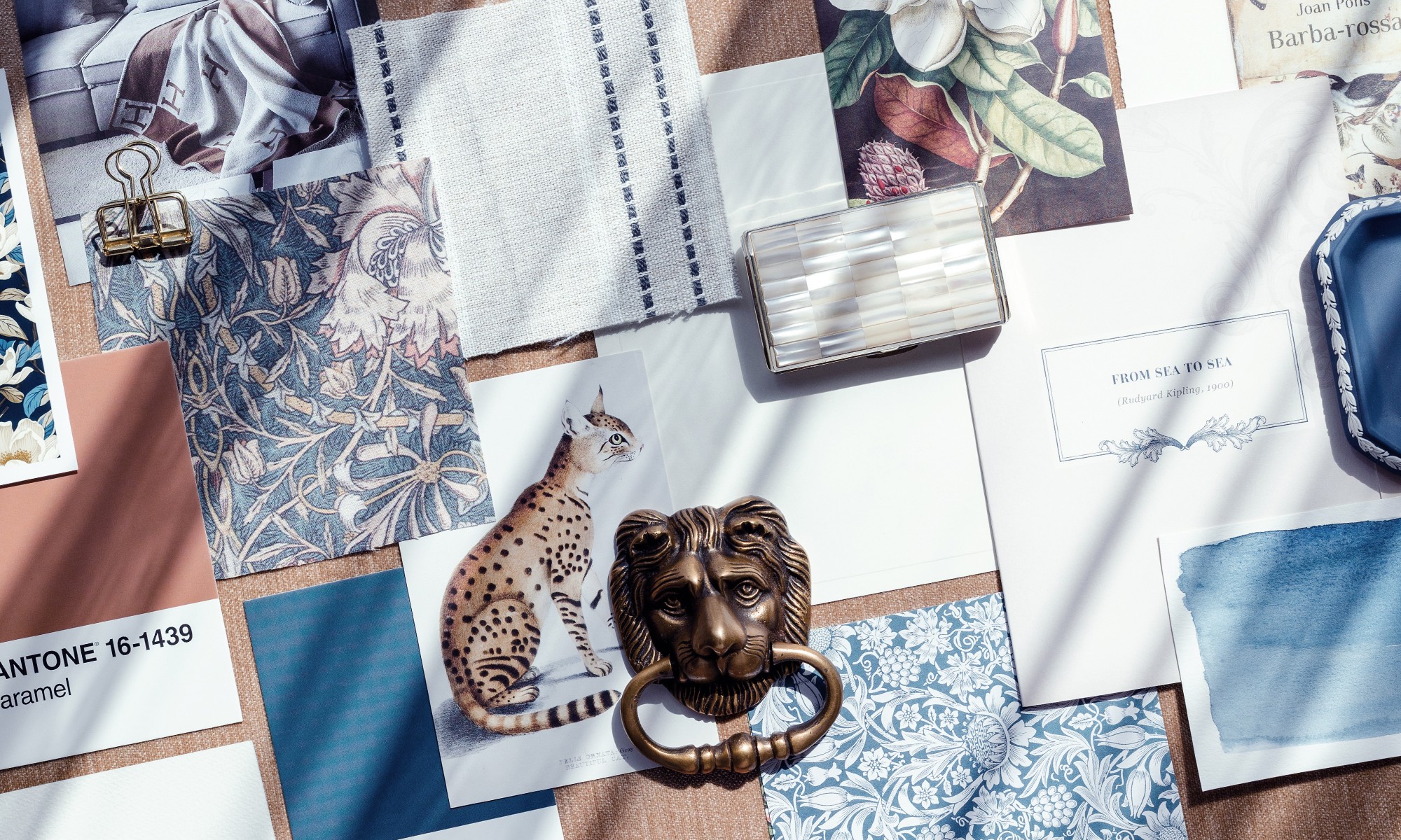 Flat lay of fabric samples, a leopard print card, a lion-shaped object, and various papers and swatches.