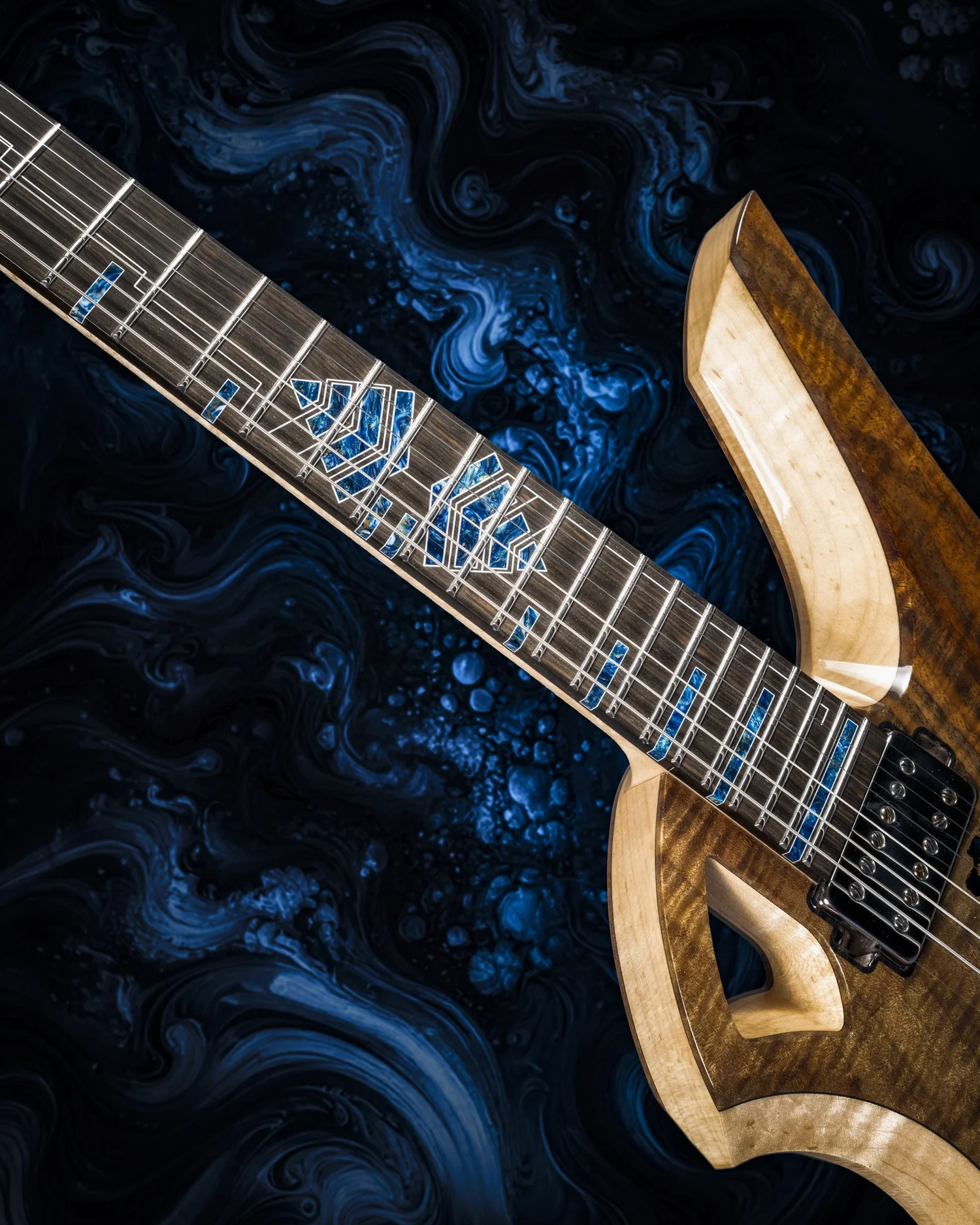Guitar neck with fretboard and inlays, against a dark blue marbled background.