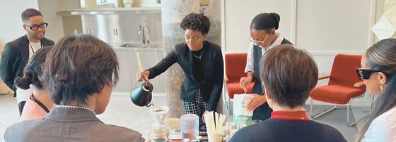 Group of people gathered around a table in a meeting room, with a woman pouring a drink.