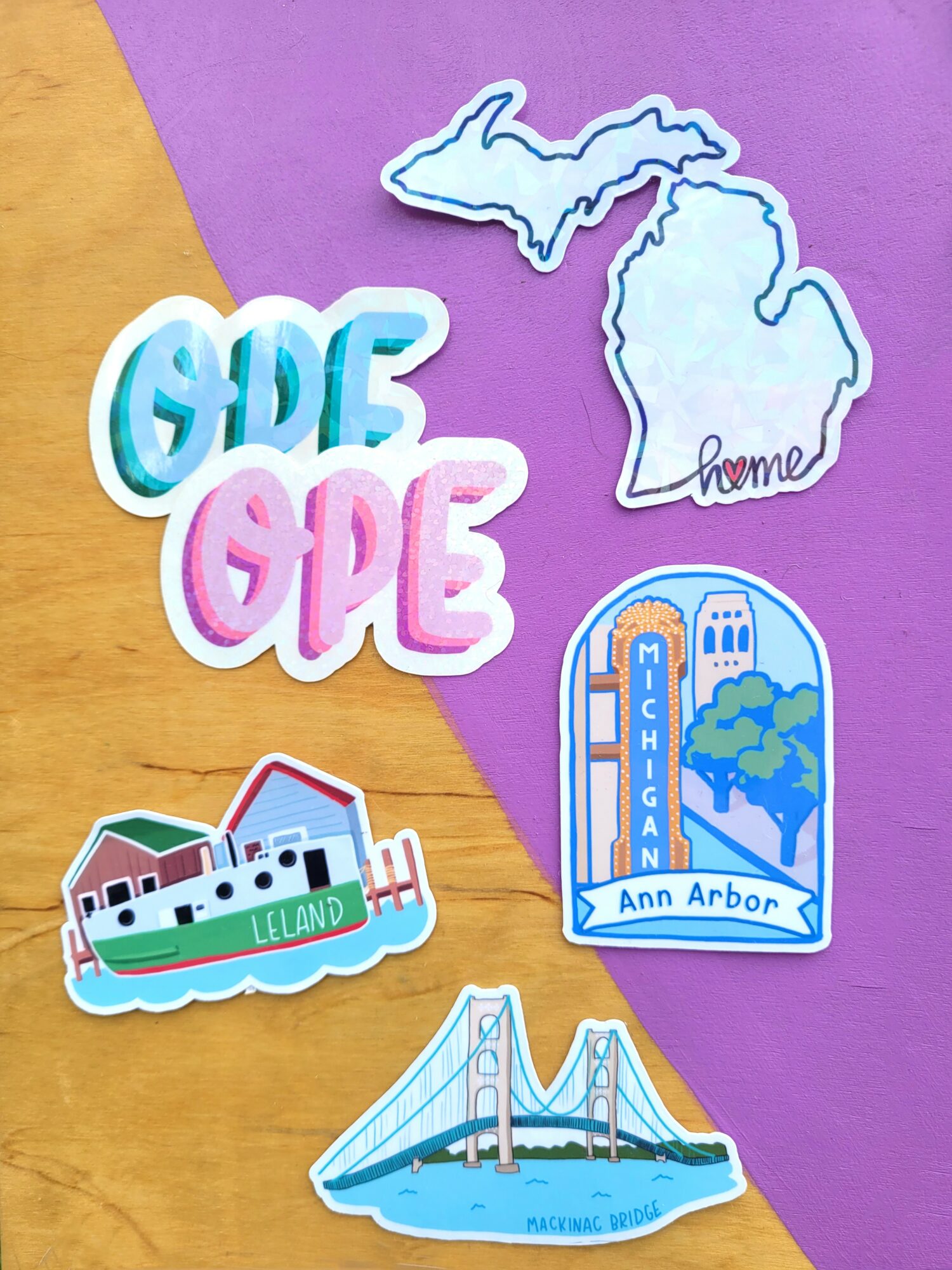 Collection of Michigan-themed stickers including 'OPE' in pink and blue, a map outline, and landmarks like a bridge and cityscape.