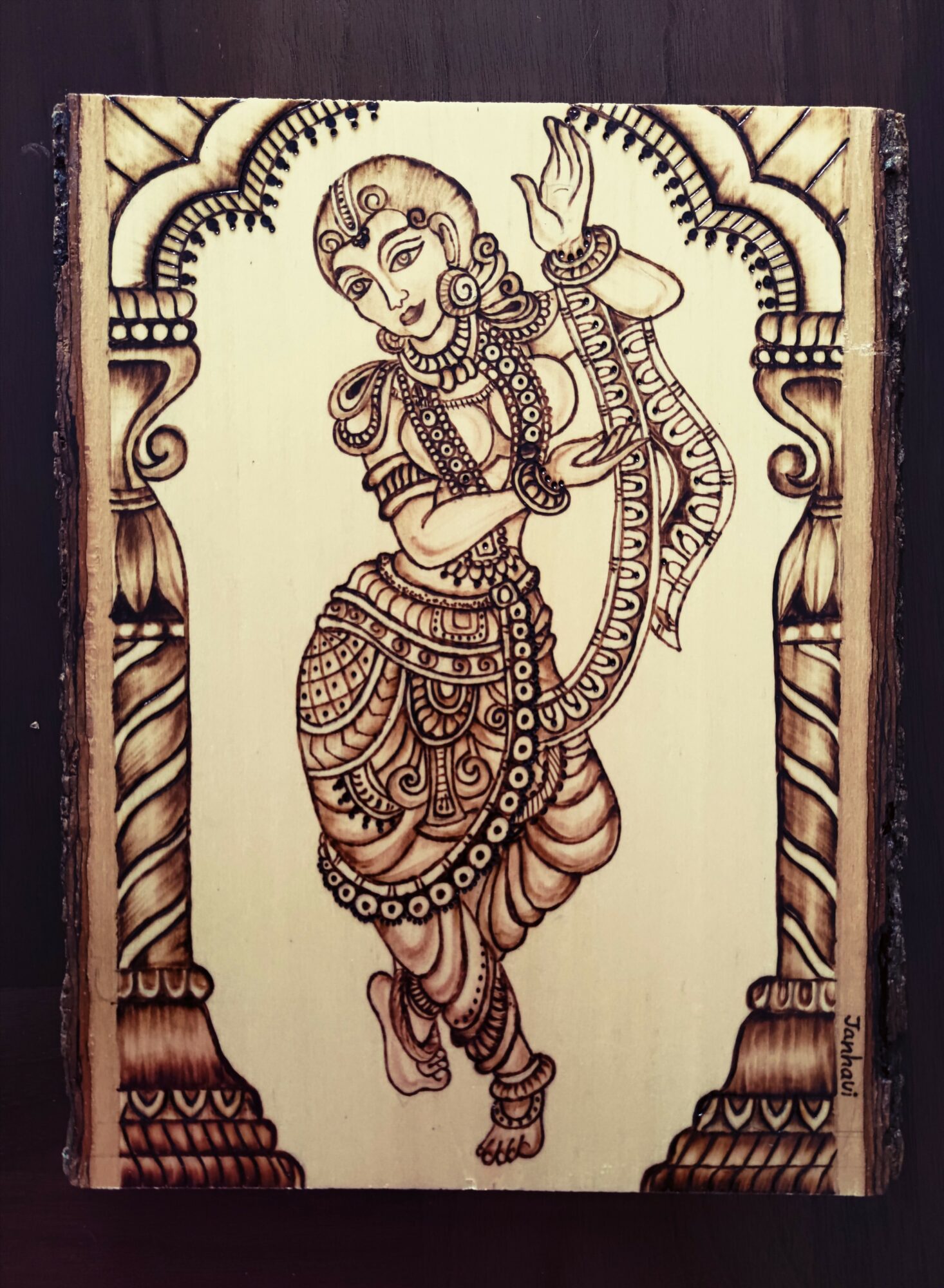Wooden panel with a detailed line drawing of a dancing figure, surrounded by an ornate arch, in traditional attire.