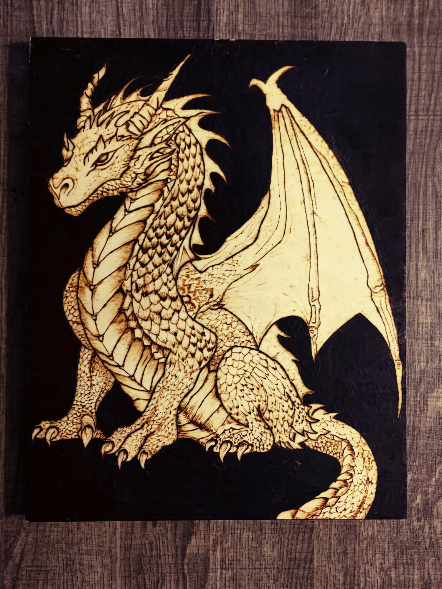 Golden dragon with detailed scales and wings on a black background, facing left, sitting on its hind legs.