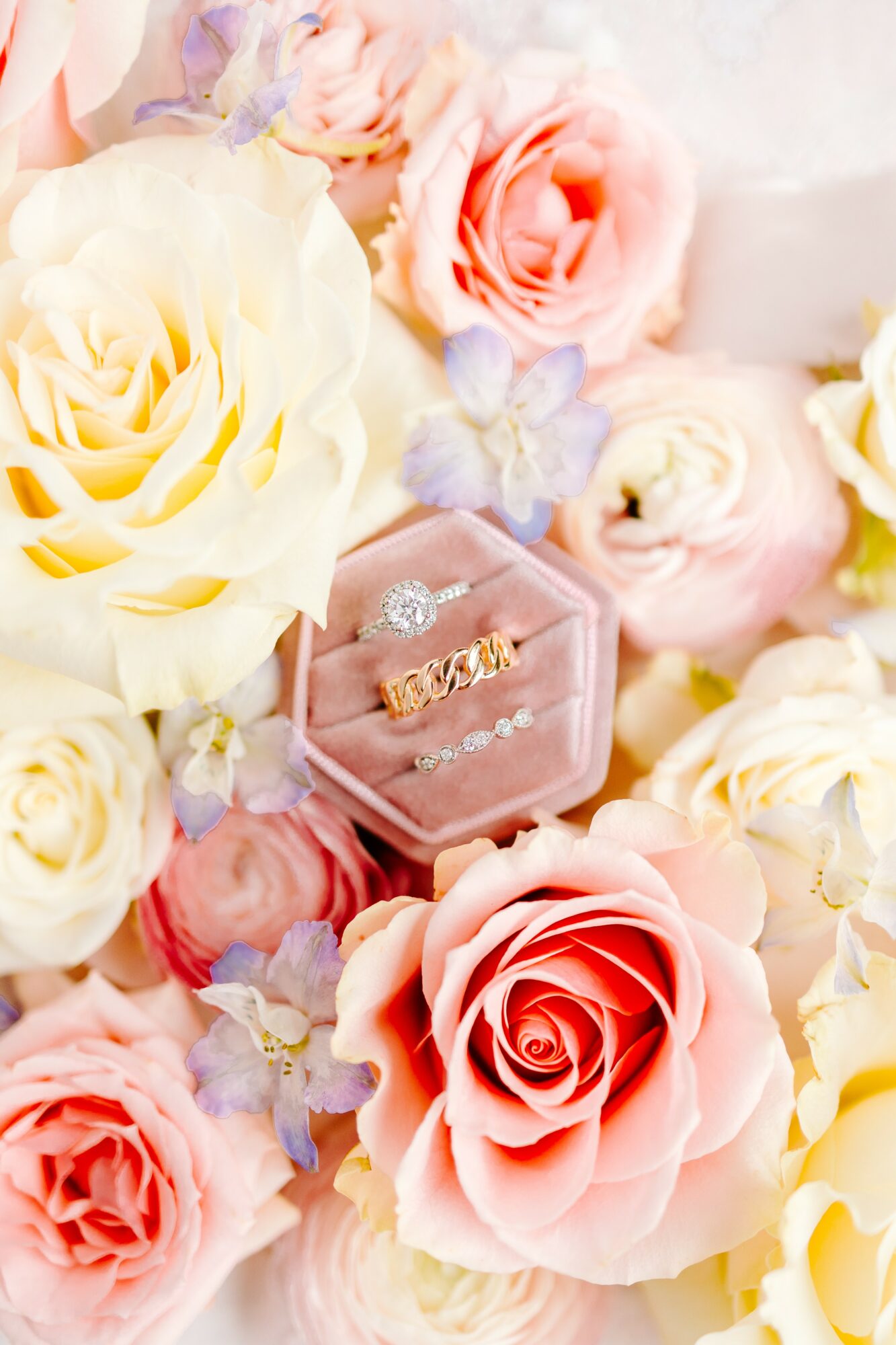 Pink and cream roses with a diamond ring in a pink box surrounded by flowers.