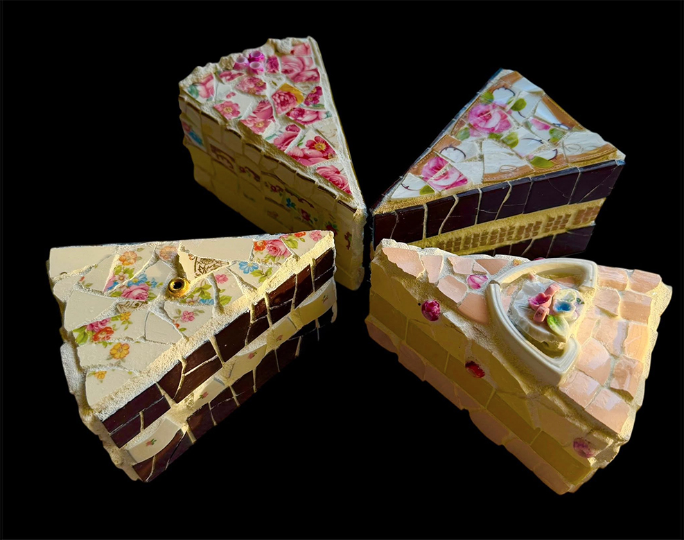 Four decorated cake slices arranged in a circle on a black background, each with different floral and cream decorations.