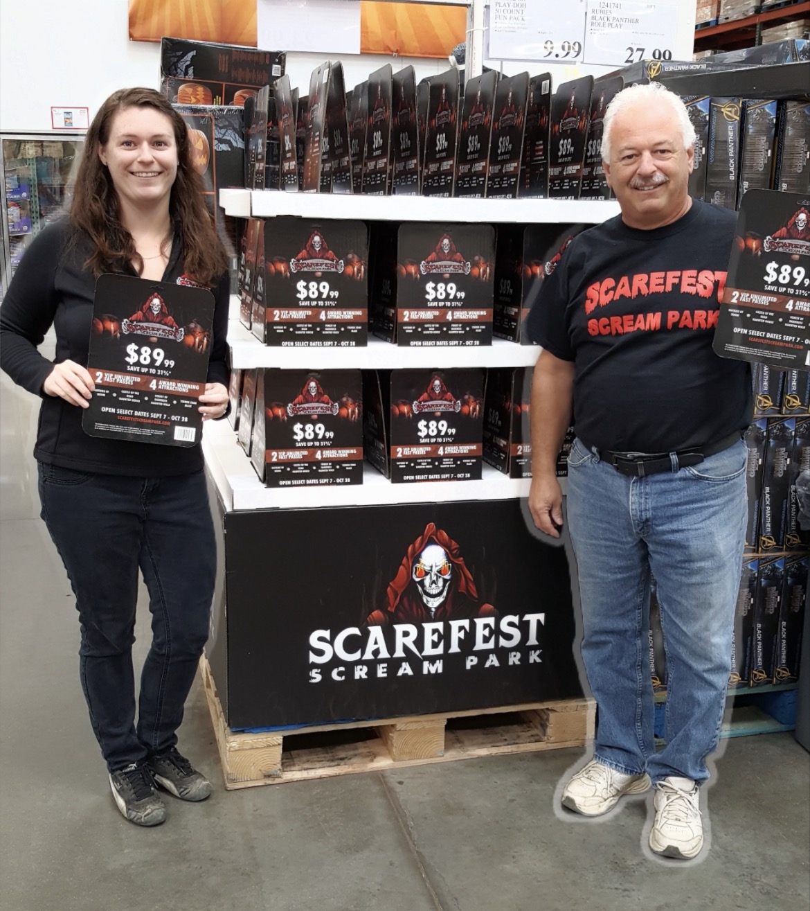 Two people standing next to a display promoting Scarefest Scream Park, holding flyers, in a store aisle.