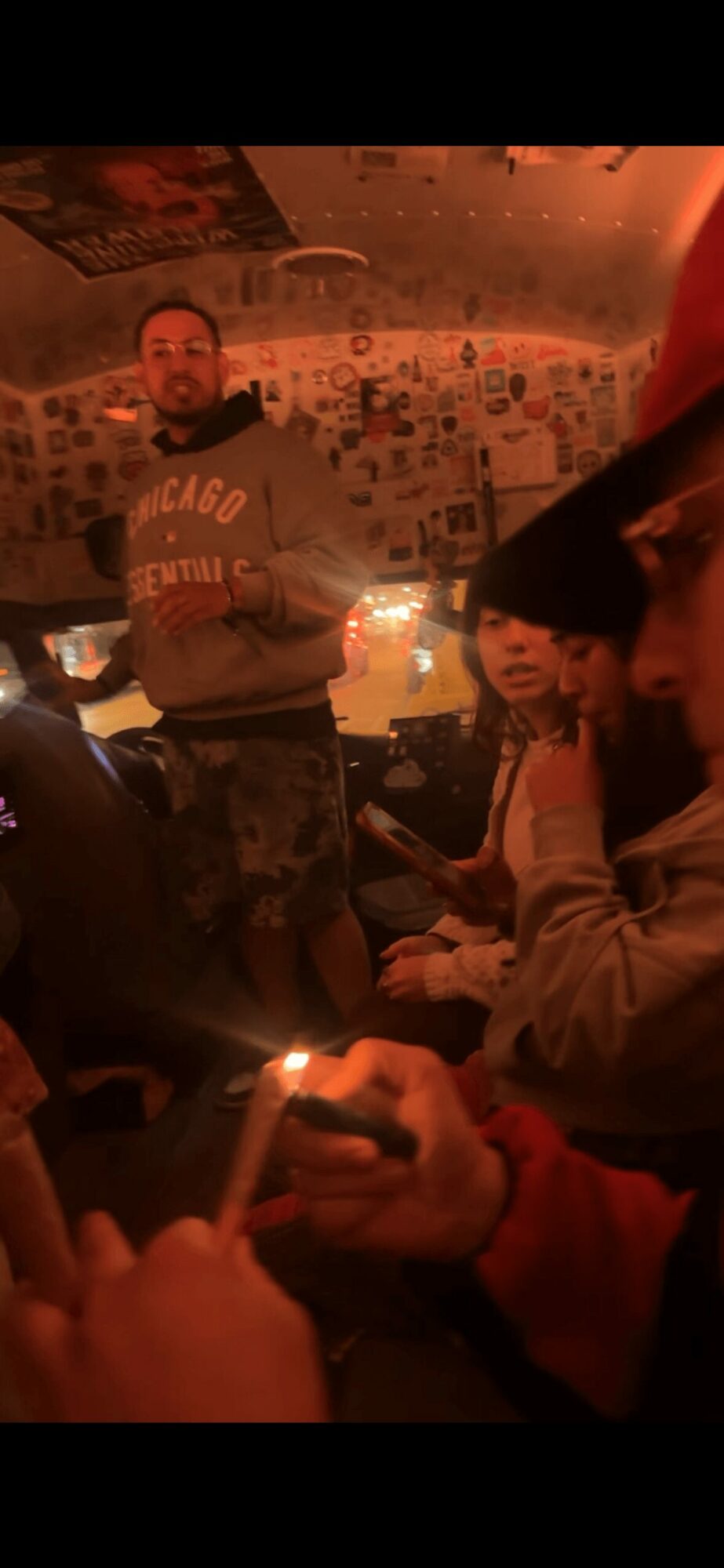 People in a dimly lit room with warm lighting, some holding candles, and a decorated ceiling in the background.