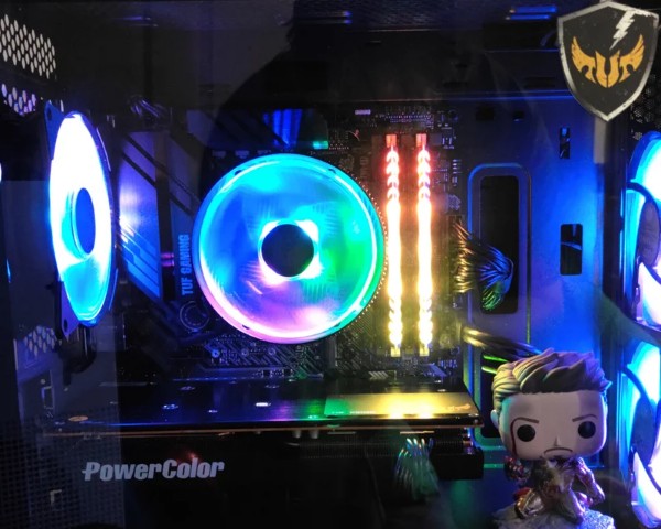 Computer interior with colorful cooling fan, RAM sticks, and a Funko Pop figure, illuminated by blue and multicolor lights.