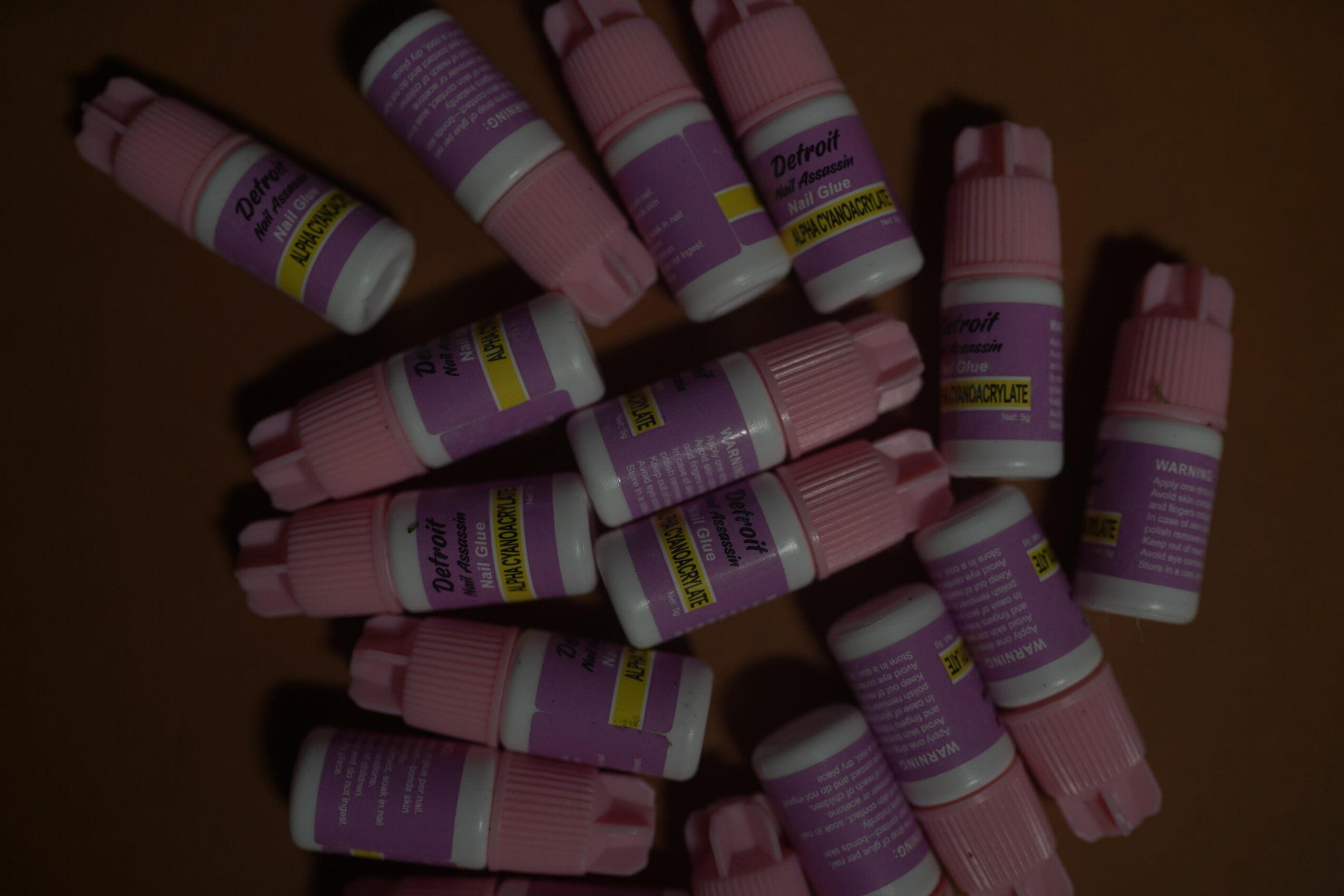 Multiple small bottles with pink and purple labels scattered on a dark surface.