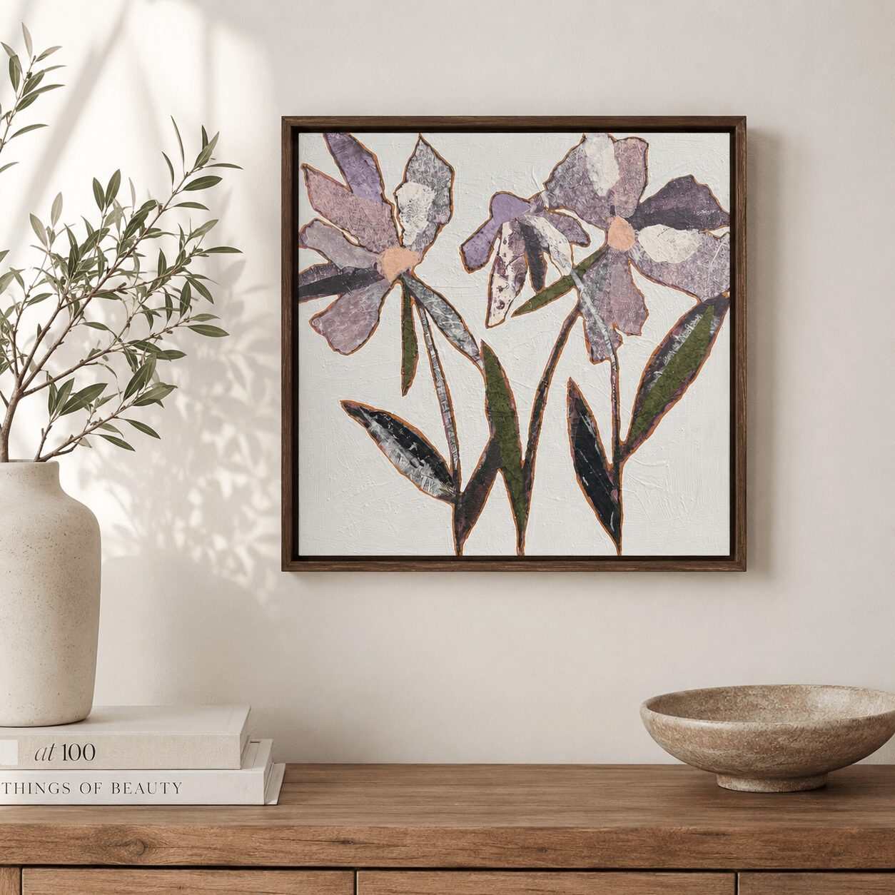 Framed floral artwork of purple and gray irises hangs on a white wall above a wooden surface.