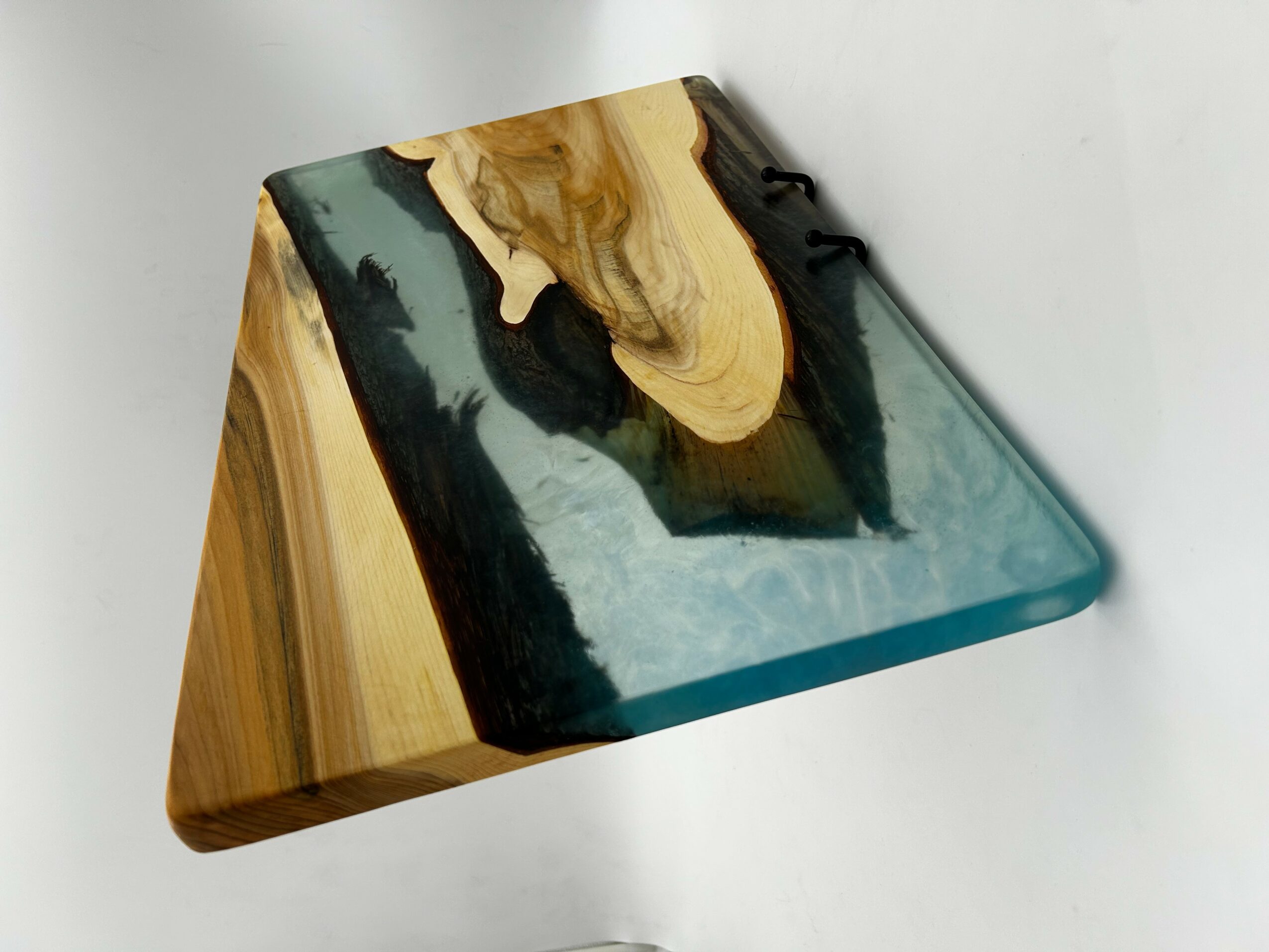 Wooden and resin art piece with black, gold, and teal colors, placed on a white surface.