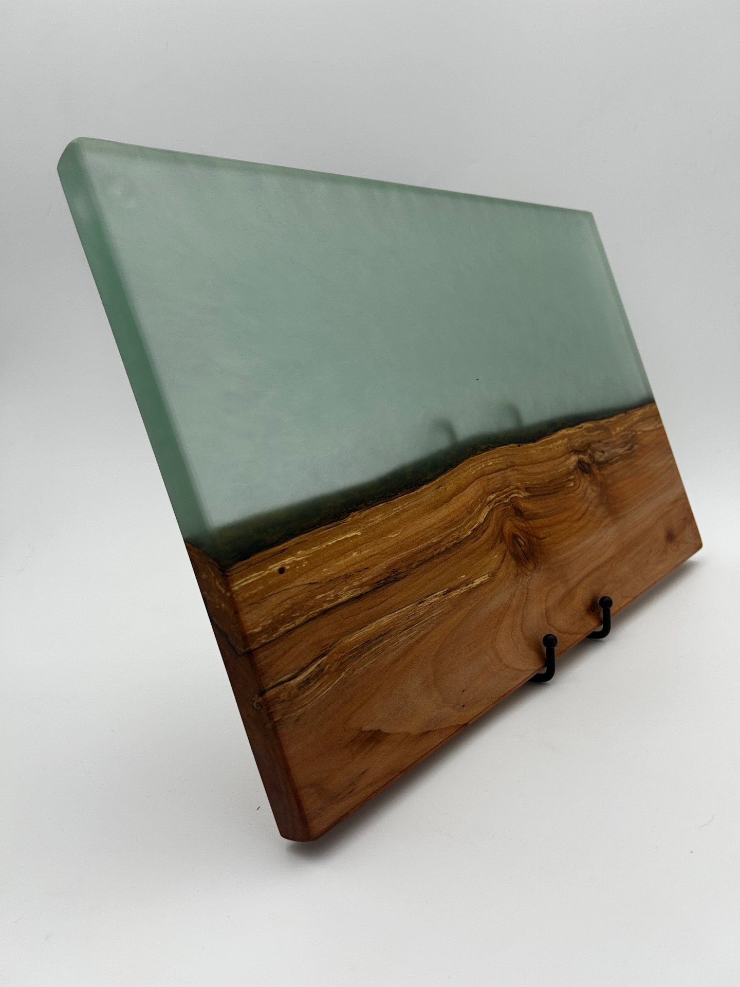 A decorative piece with a glass top and wooden base, featuring hooks on the front, against a plain background.