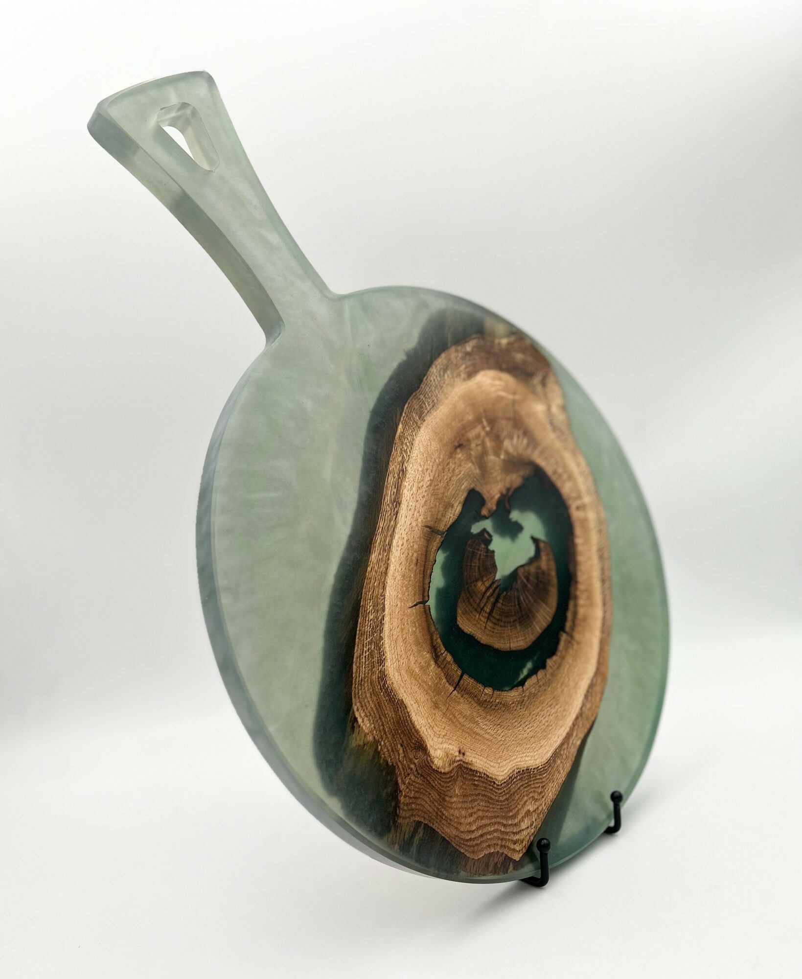 Glass vase with a wooden insert and a small handle, displayed on a stand against a plain background.