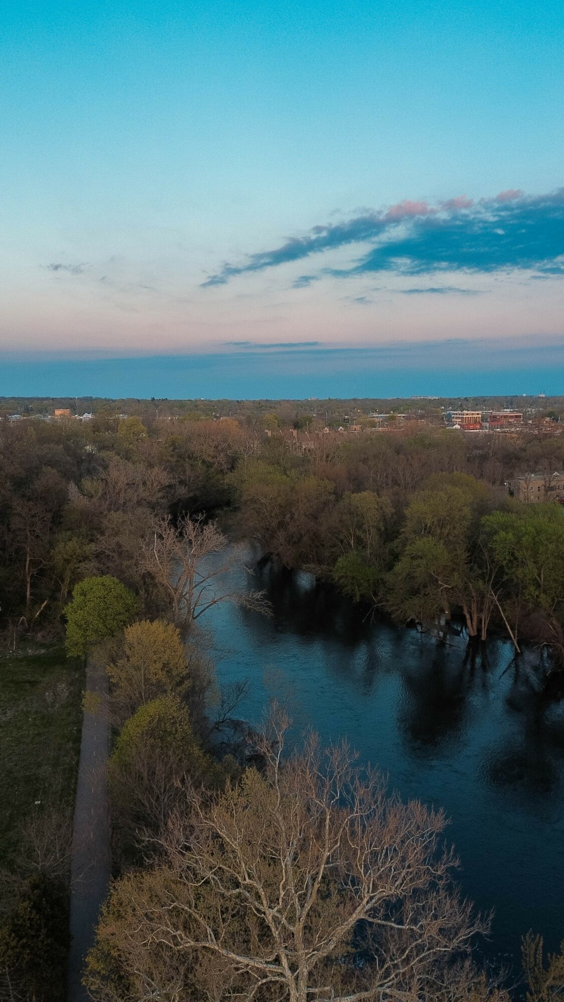 River flowing through trees with a sky and clouds above, landscape view, clear weather.