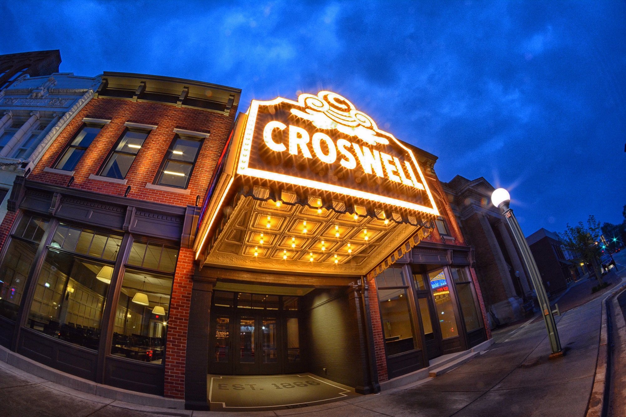 The Crossroads theater marquee illuminated at night with a blue sky background.